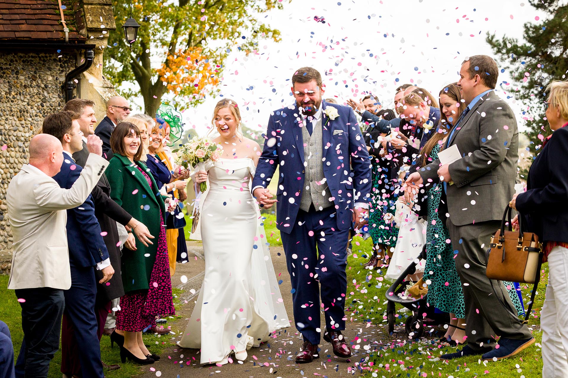 Bride and groom with confetti by Essex reportage wedding photographer at St Giles Church, Great Maplestead