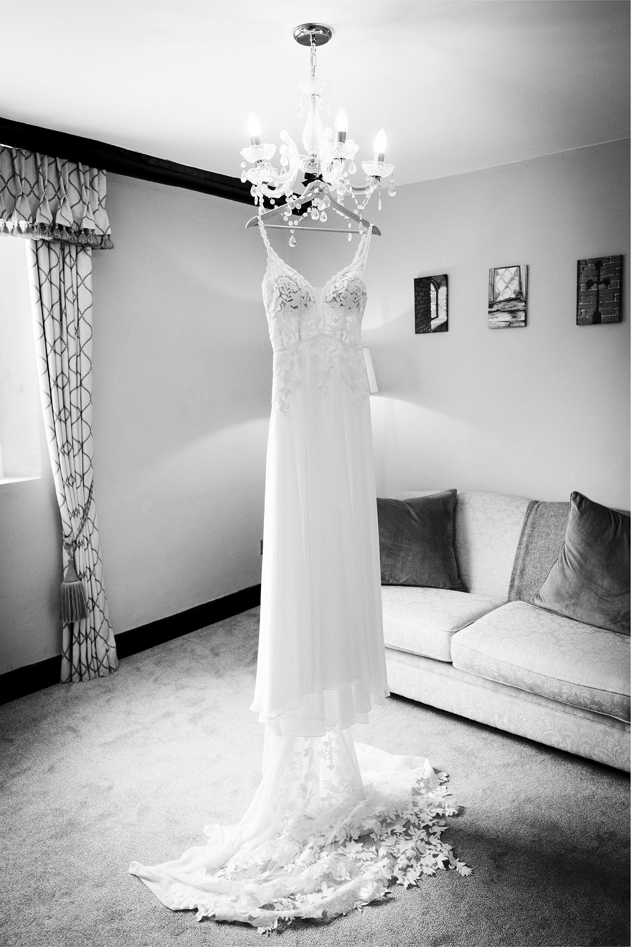 Black and white reportage wedding photography of wedding dress during bridal preparations at Leez Priory, Great Leighs, Chelmsford, Essex