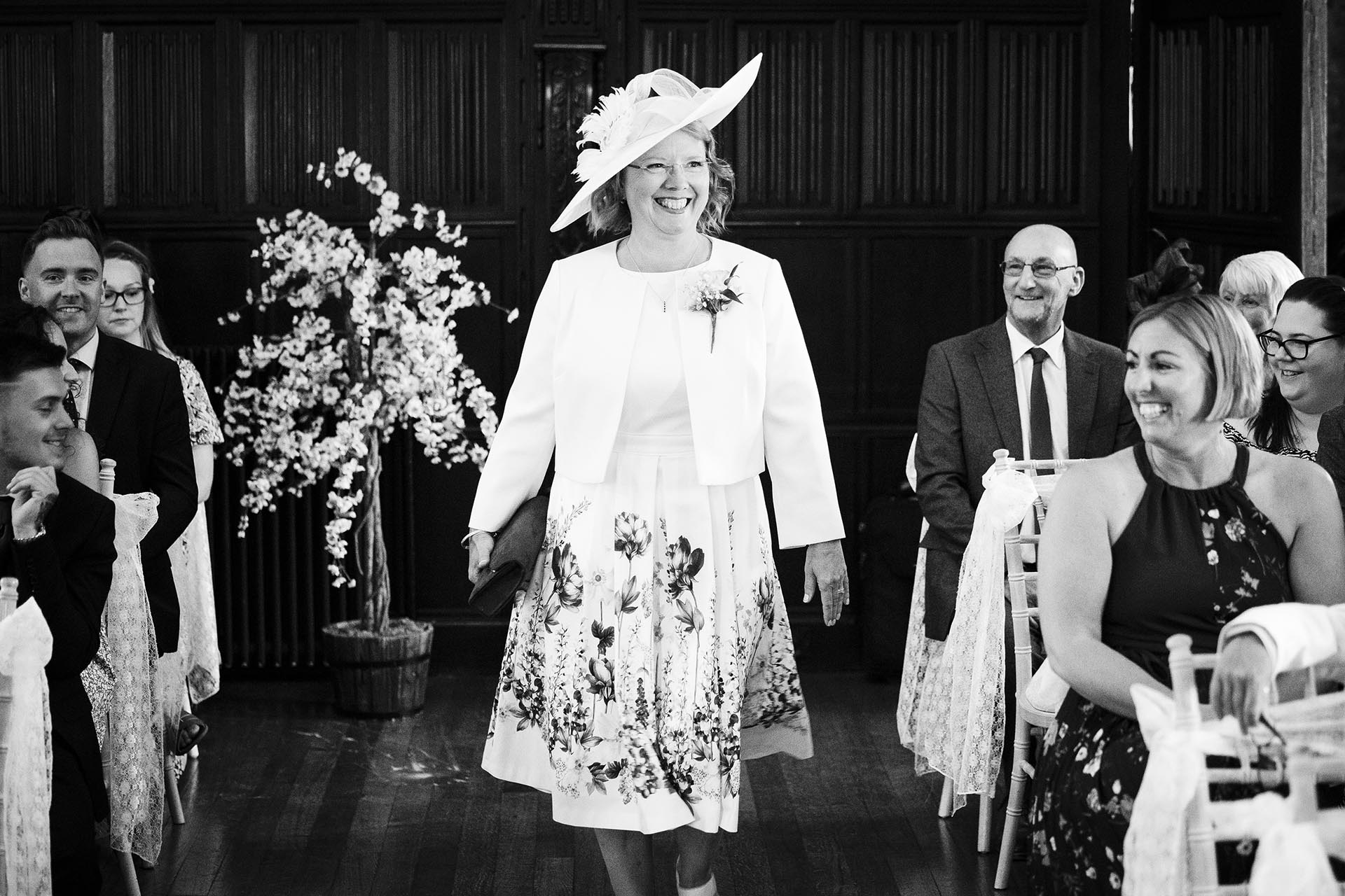 Black and white photograph of bride's mother arriving at wedding ceremony at Leez Priory, Great Leighs, Chelmsford by Essex wedding photographer