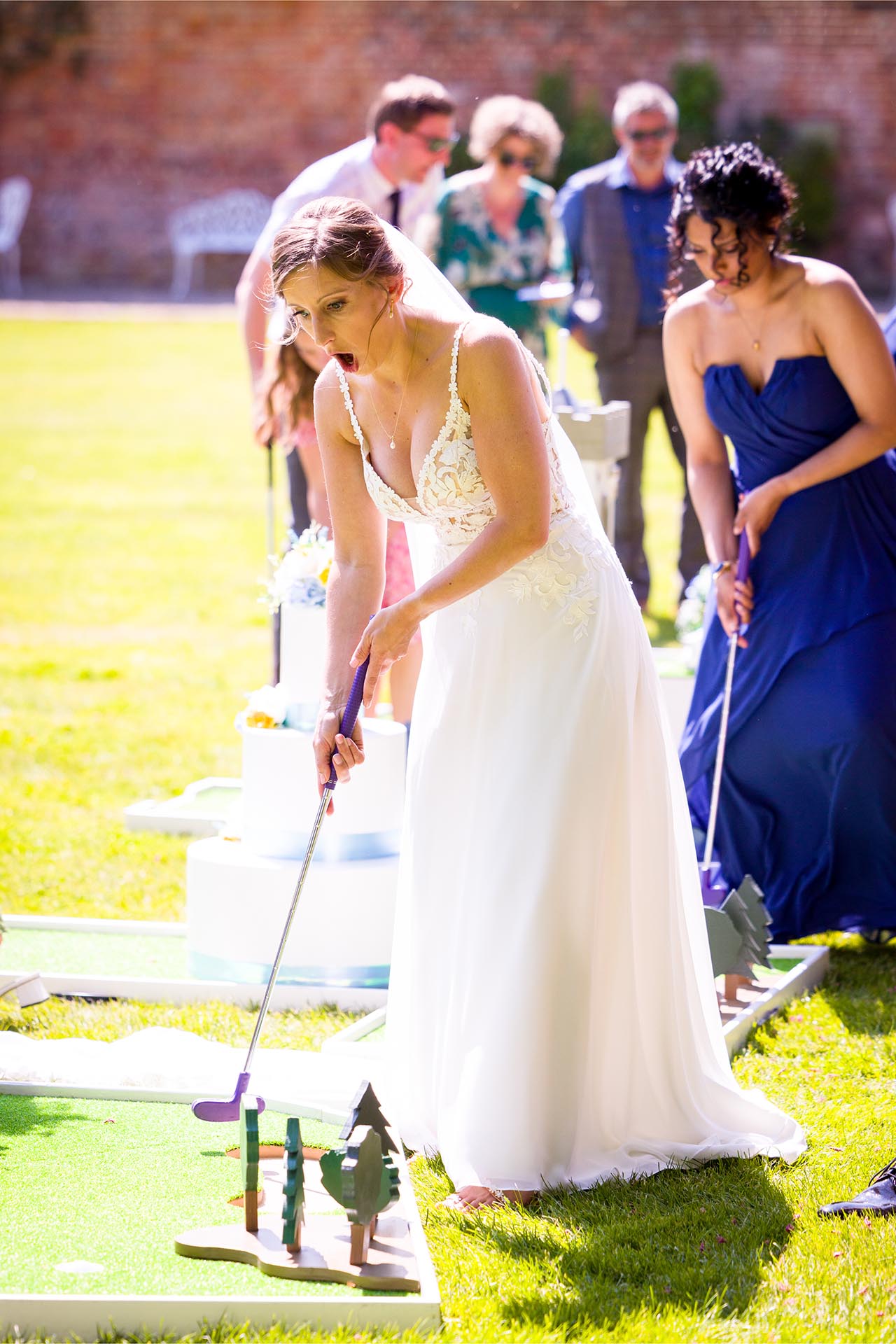 Bride playing crazy golf at a summer Leez Priory wedding, Great Leighs, Chelmsford, by Essex wedding photographer