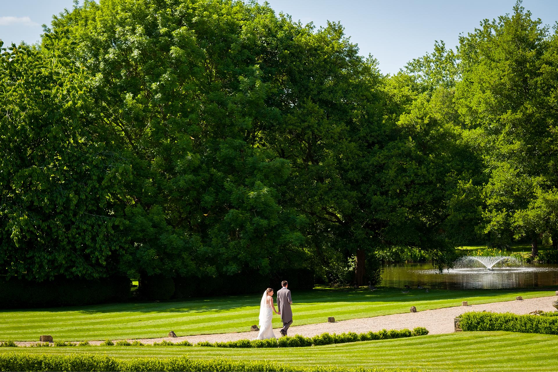 Bride and groom walking through the grounds at a Leez Priory wedding, Great Leighs, Chelmsford, by Essex wedding photographer