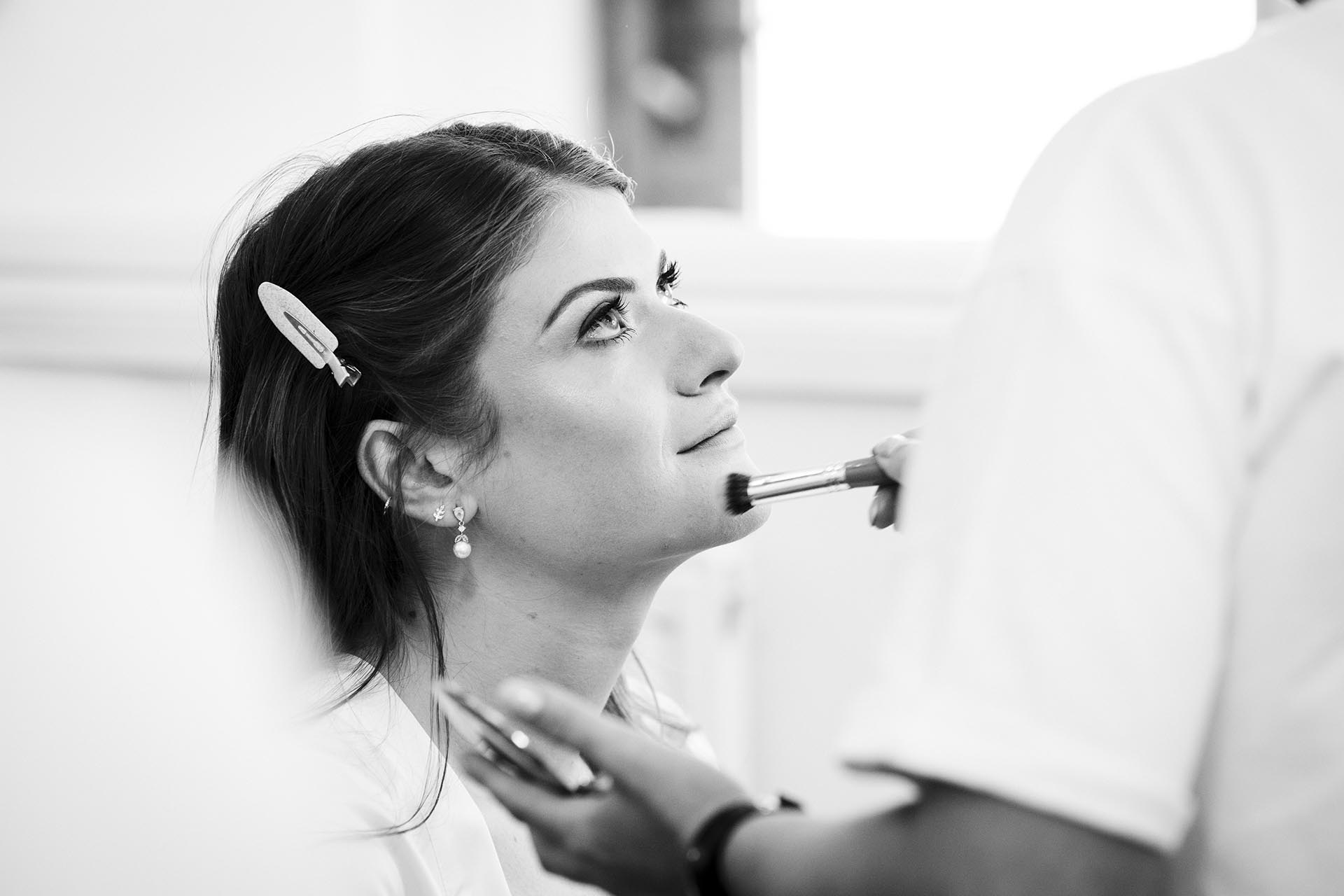 Black and white photograph of the bride having her makeup done at Apton Hall, Rochford, Essex