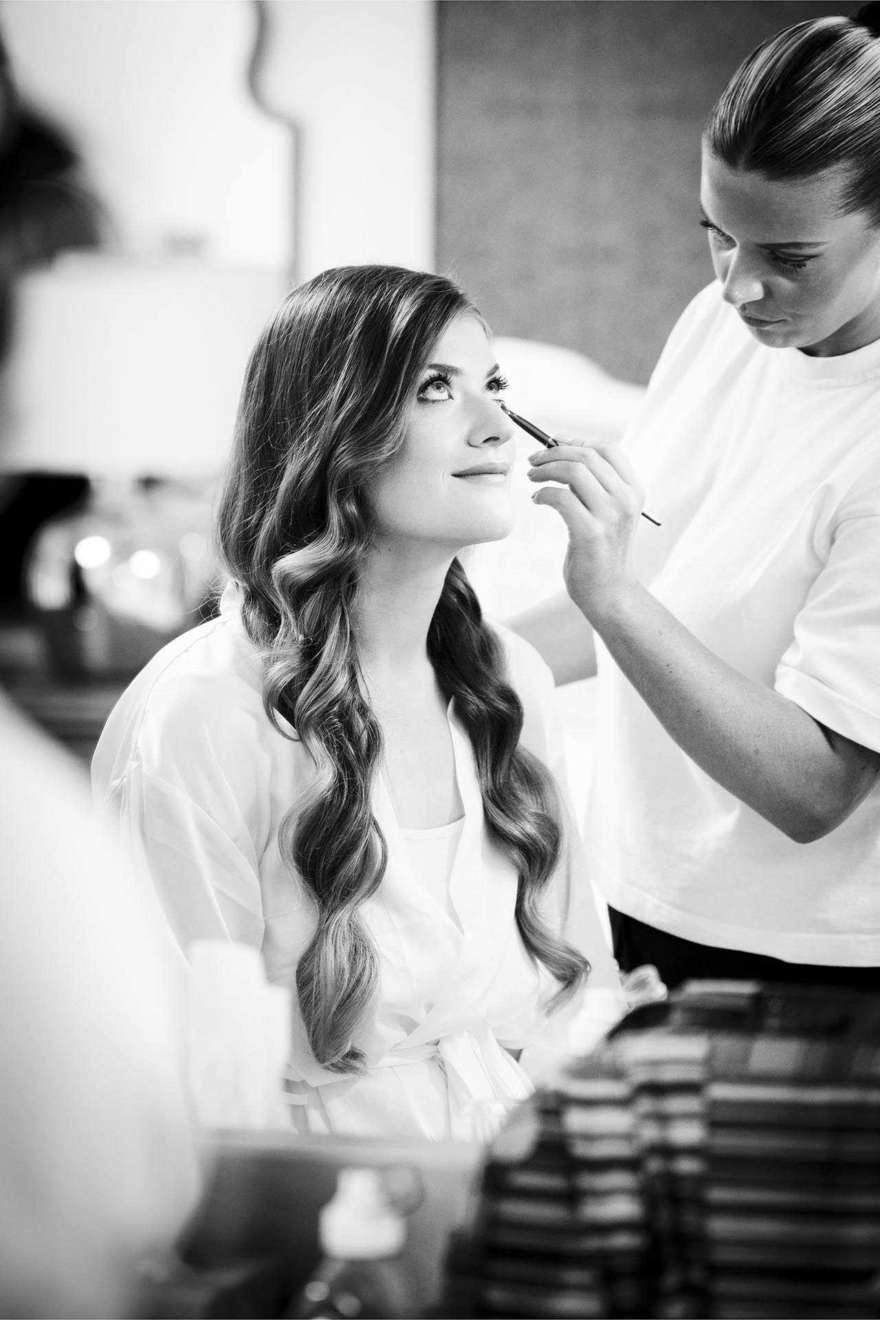 Black and white photograph of the bride having her makeup done at Apton Hall, Rochford, Essex
