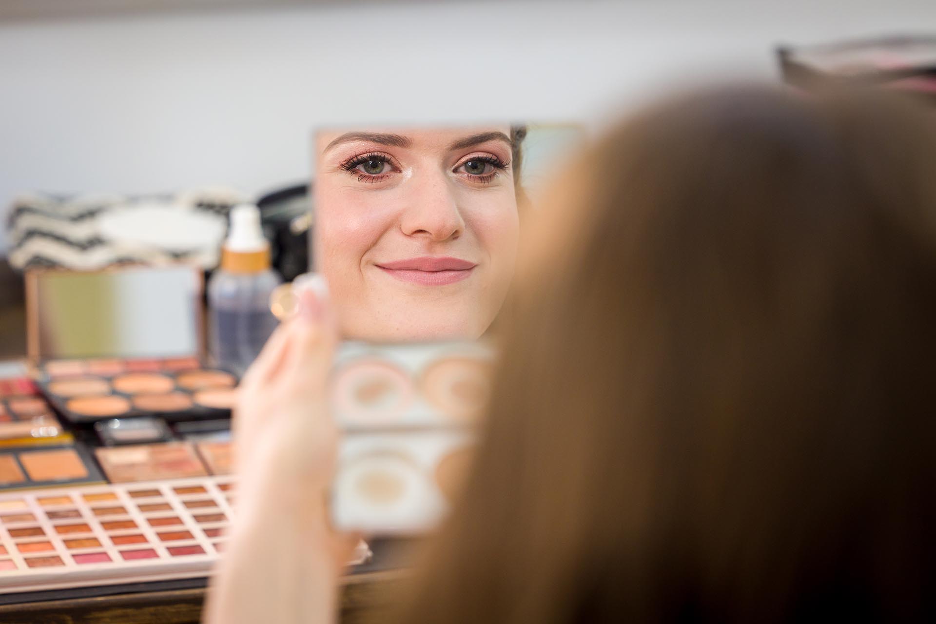 Photograph of the bride looking at herself in a makeup mirror at Apton Hall, Rochford, Essex