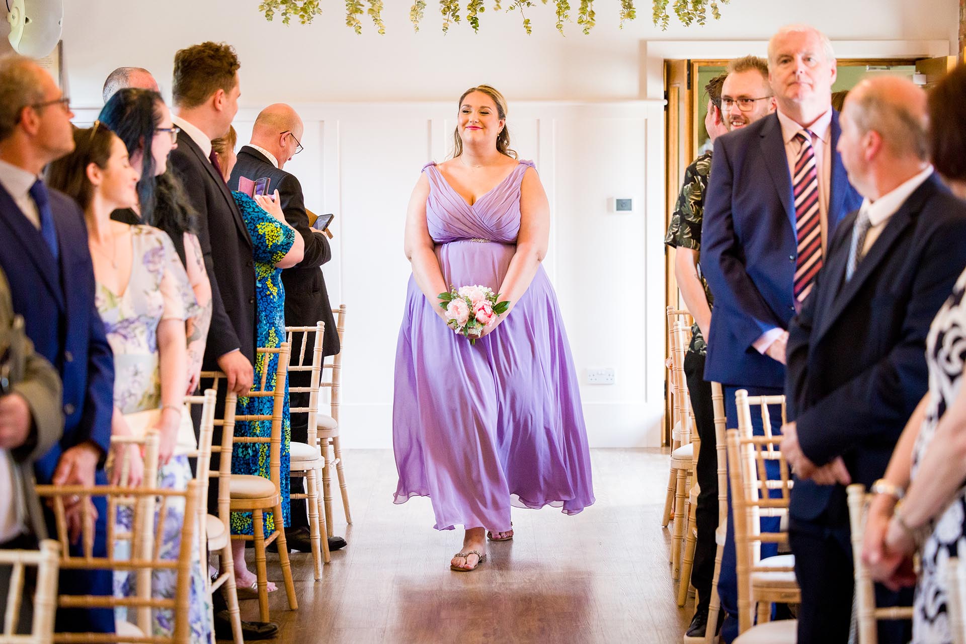 Photograph of a bridesmaid walking down the aisle for the wedding ceremony at Apton Hall, Rochford, Essex