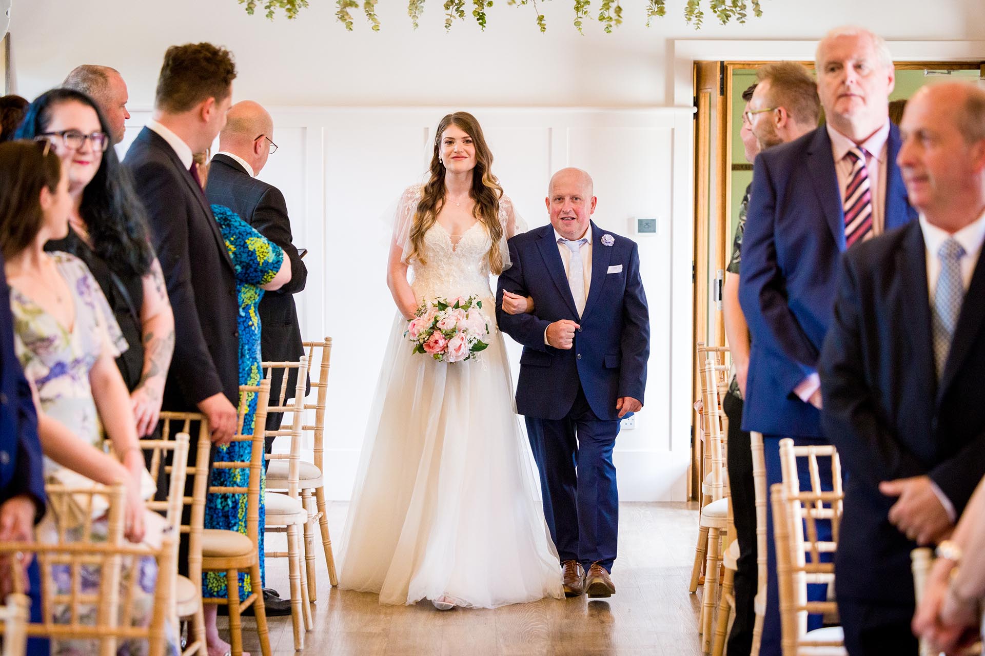 Photograph of bride and her father walking down the aisle for the wedding ceremony at Apton Hall, Rochford, Essex