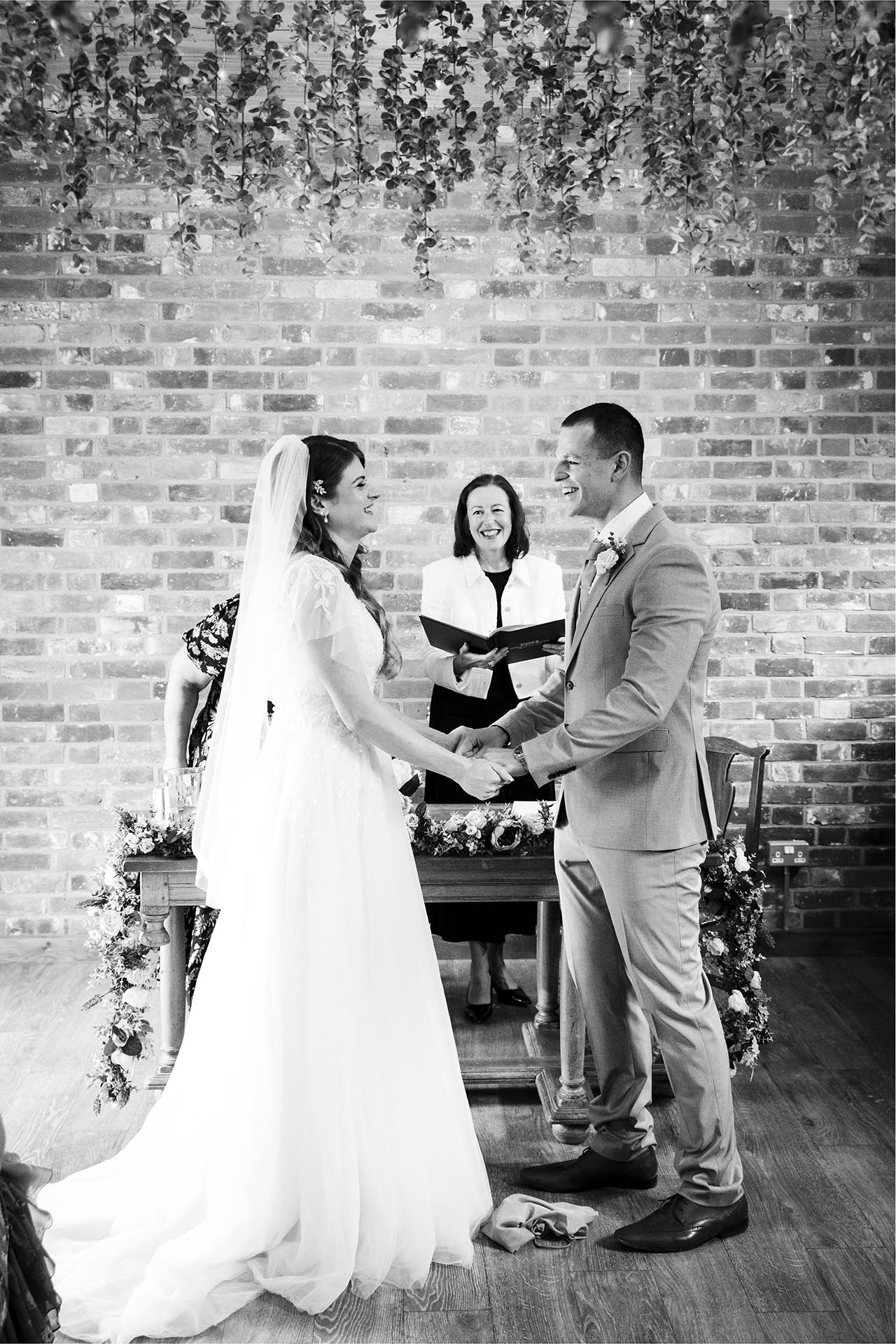 Photograph of the bride and groom laughing in ceremony room at Apton Hall, Rochford, Essex