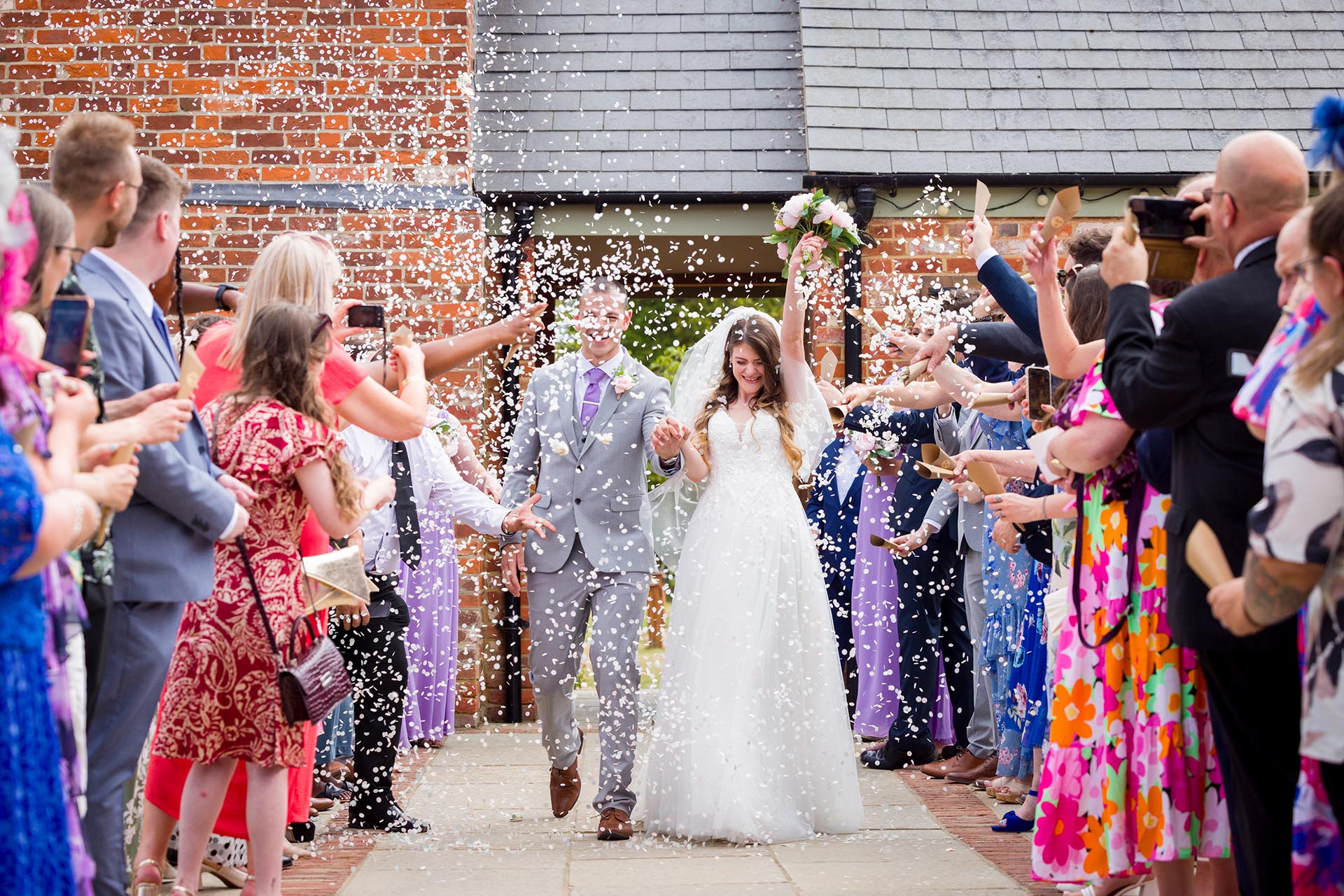 Photograph of the bride and groom walking through confetti at Apton Hall, Rochford, Essex