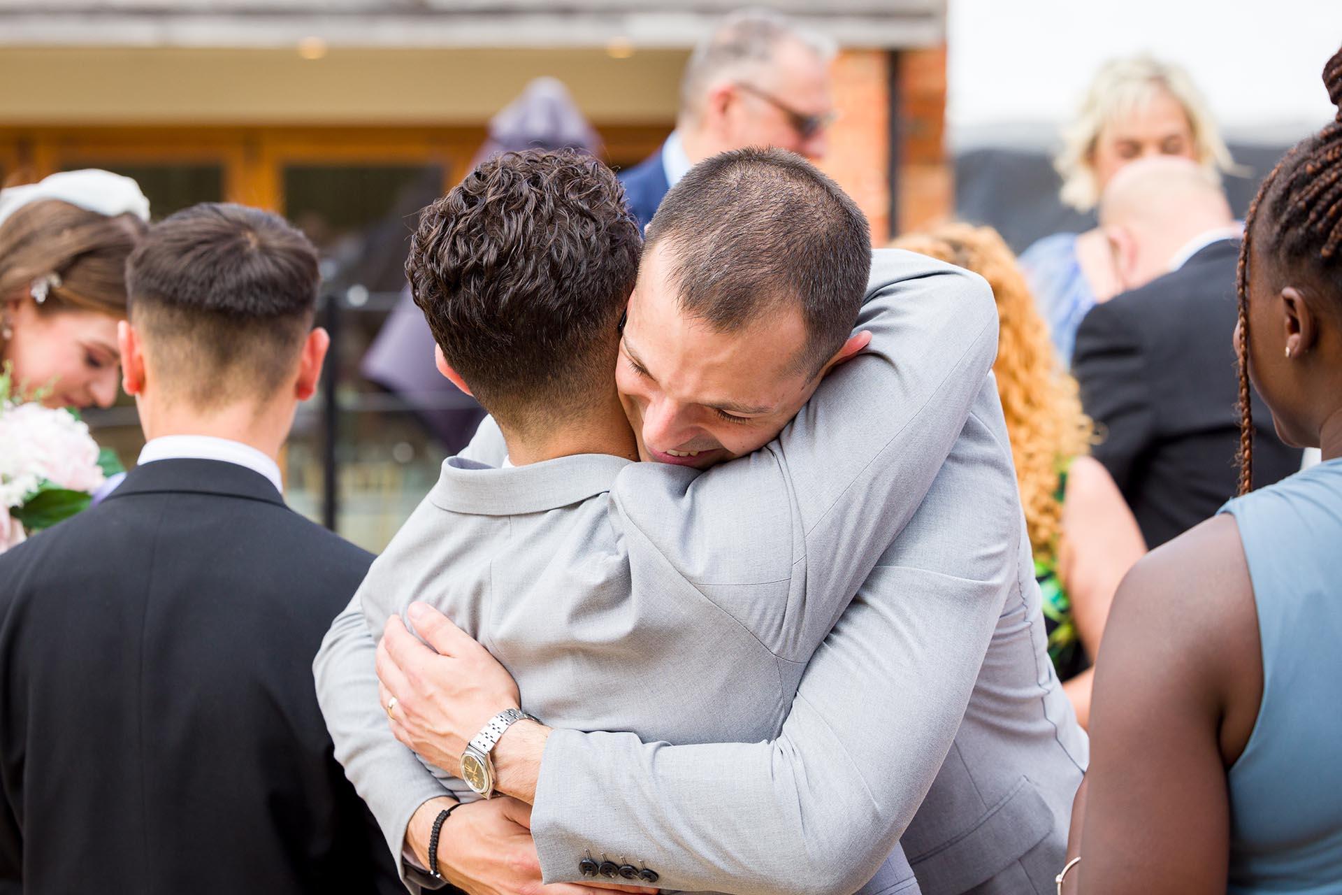 Candid photograph of the groom hugging a wedding guest at Apton Hall, Rochford, Essex