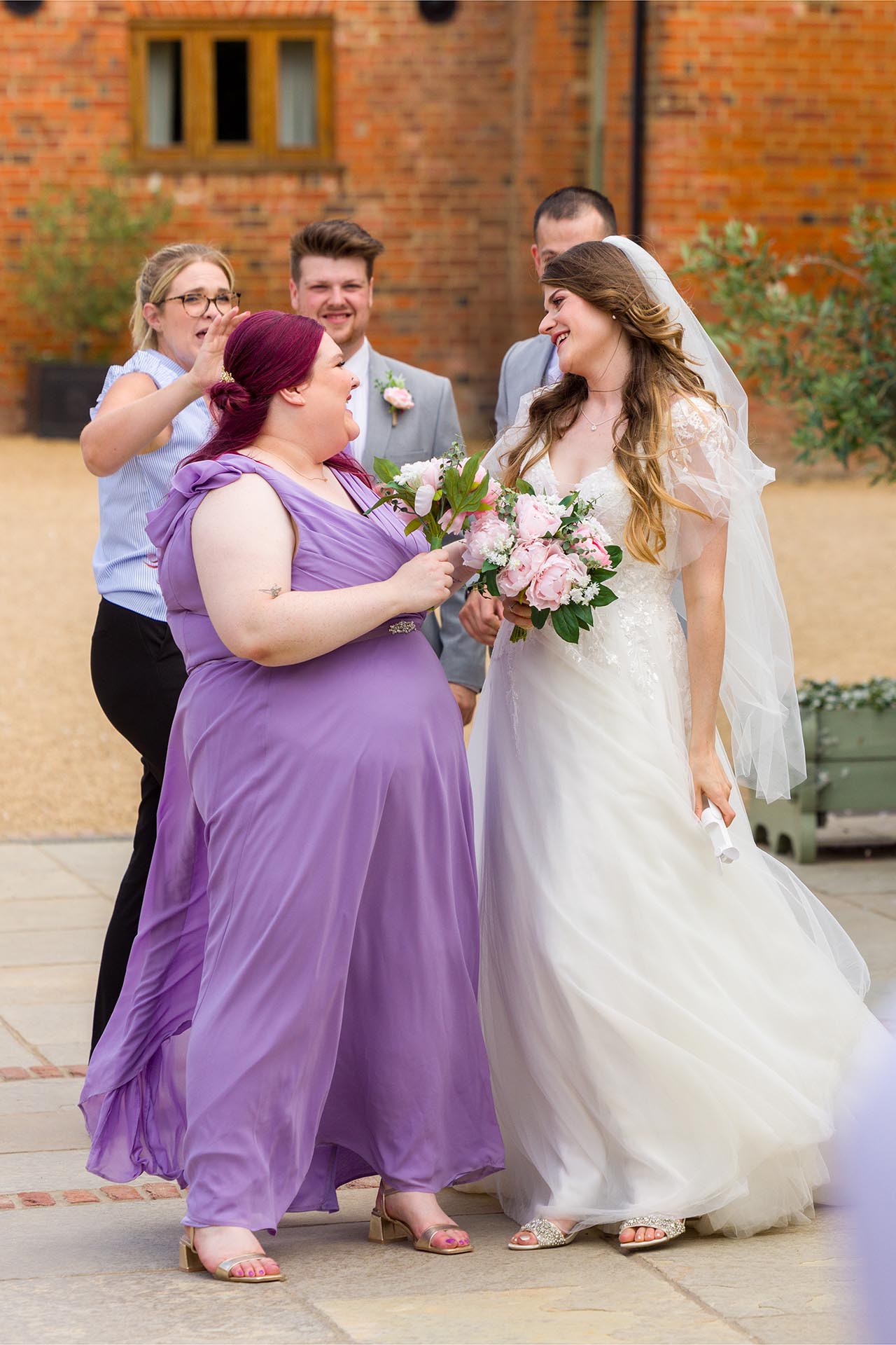 Candid photograph of the bride and a bridesmaid laughing at Apton Hall, Rochford, Essex