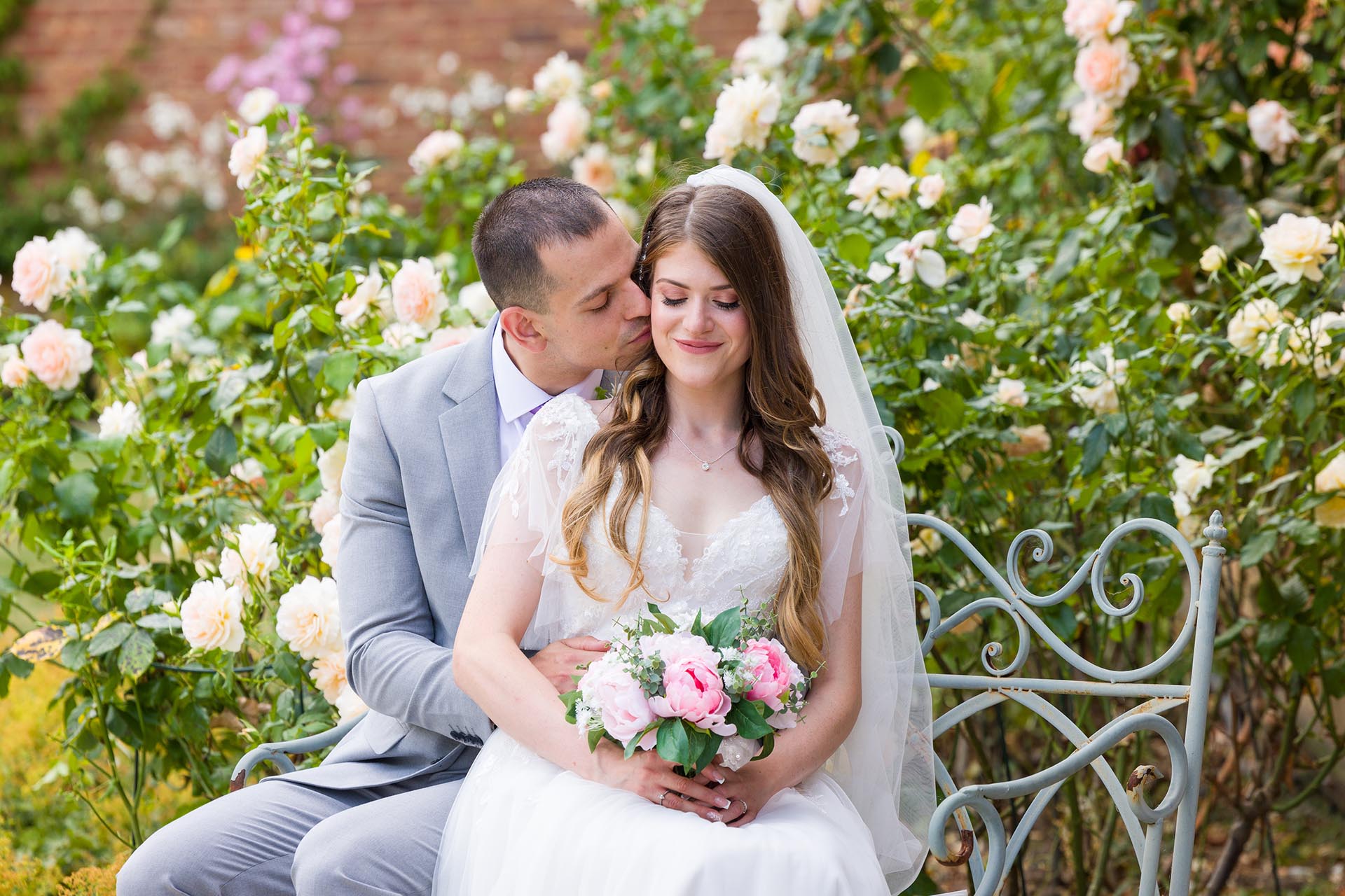 Photograph of the bride and groom surrounded by roses at Apton Hall, Rochford, Essex