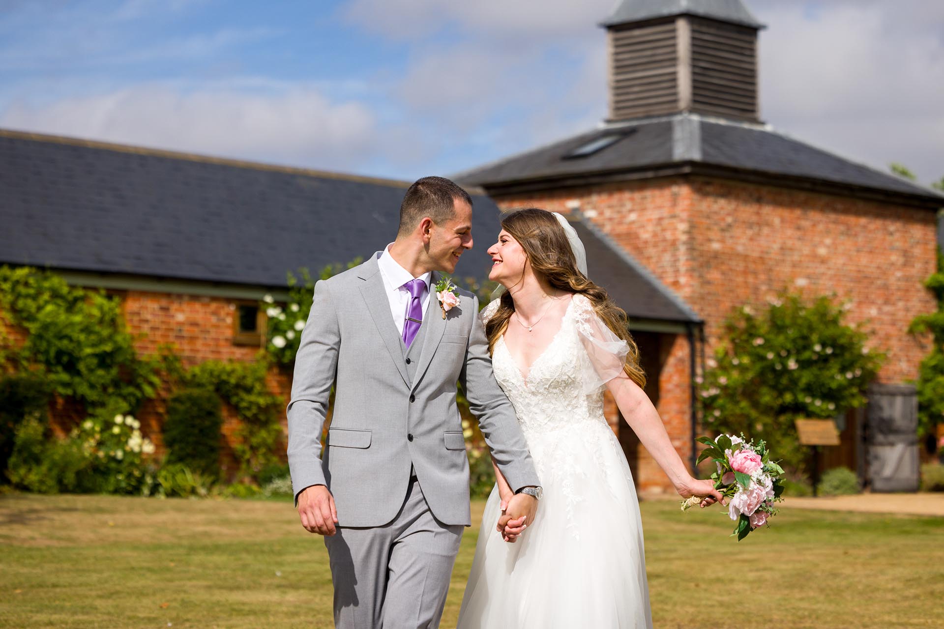 Photograph of the bride and groom tlaughing as they walk across the lawn at Apton Hall, Rochford, Essex