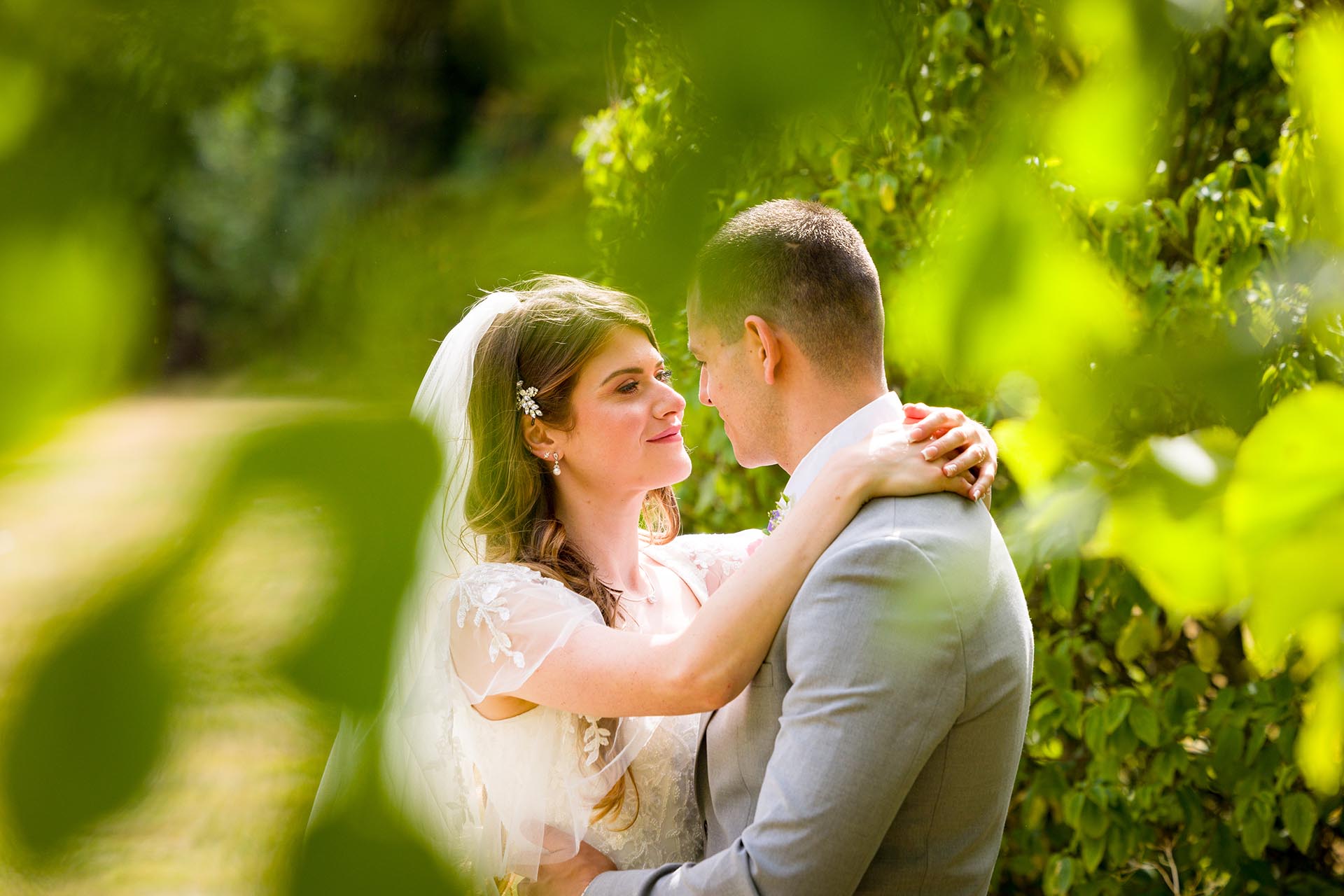 Photograph of the bride and groom through foliage at Apton Hall, Rochford, Essex