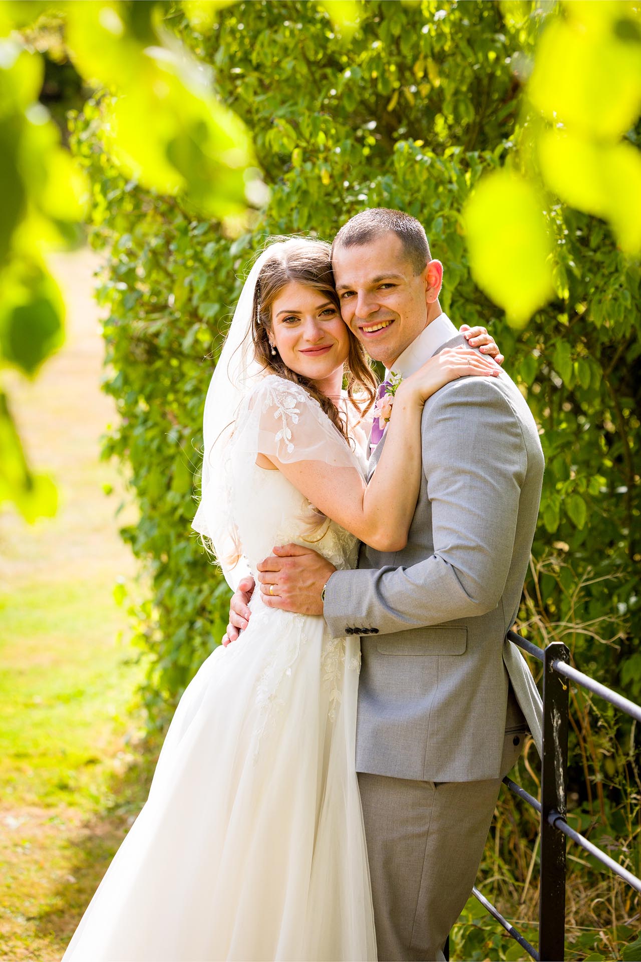 Photograph of the bride and groom through foliage at Apton Hall, Rochford, Essex
