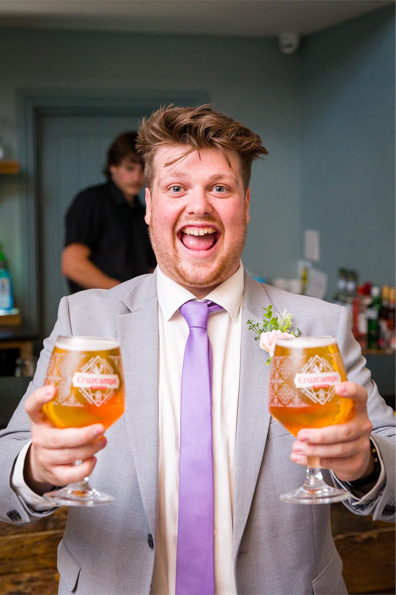 Photograph of a happy wedding guest with two glasses of beer at Apton Hall, Rochford, Essex
