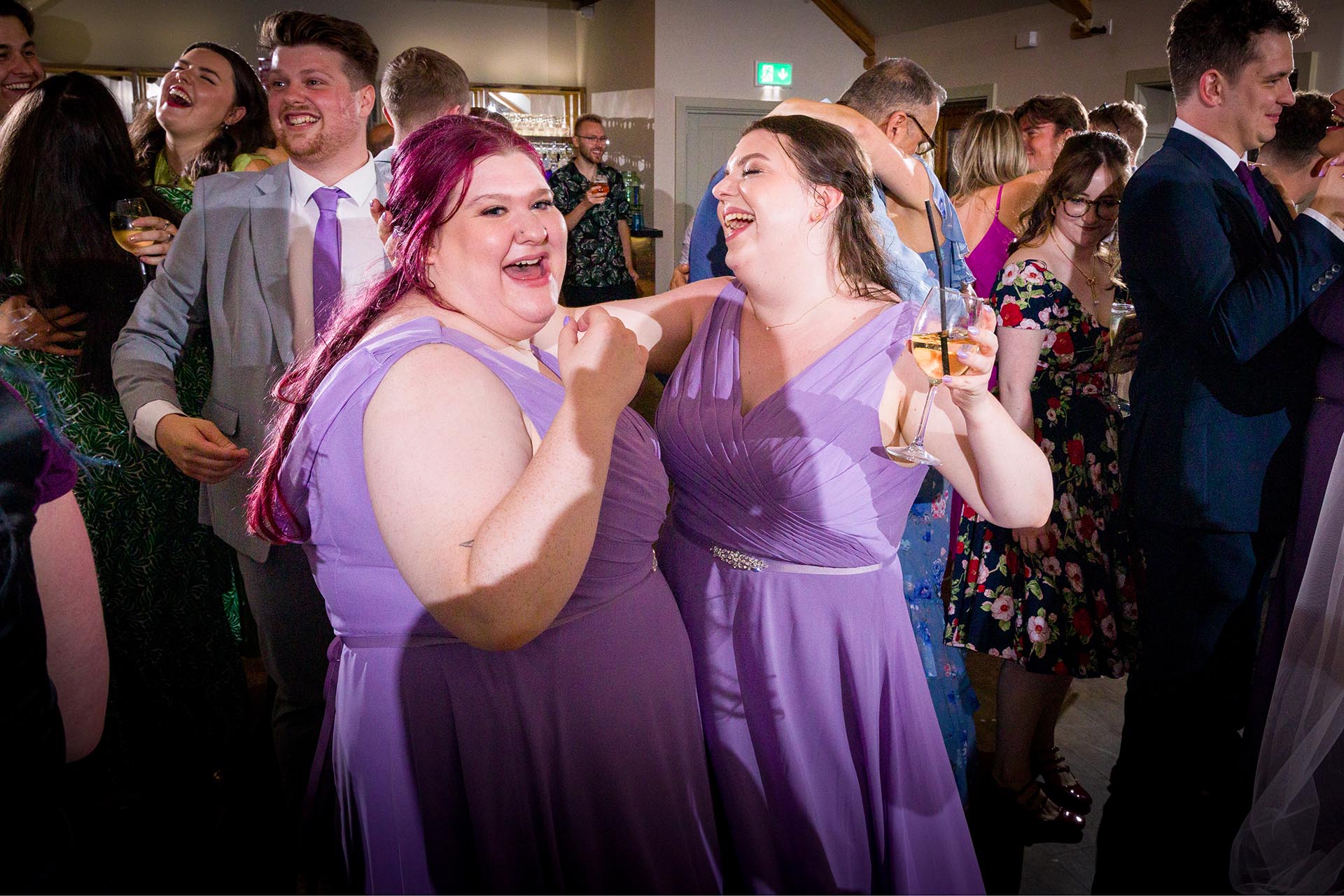 Colourful photograph of wedding bridesmaids dancing at Apton Hall, Rochford, Essex