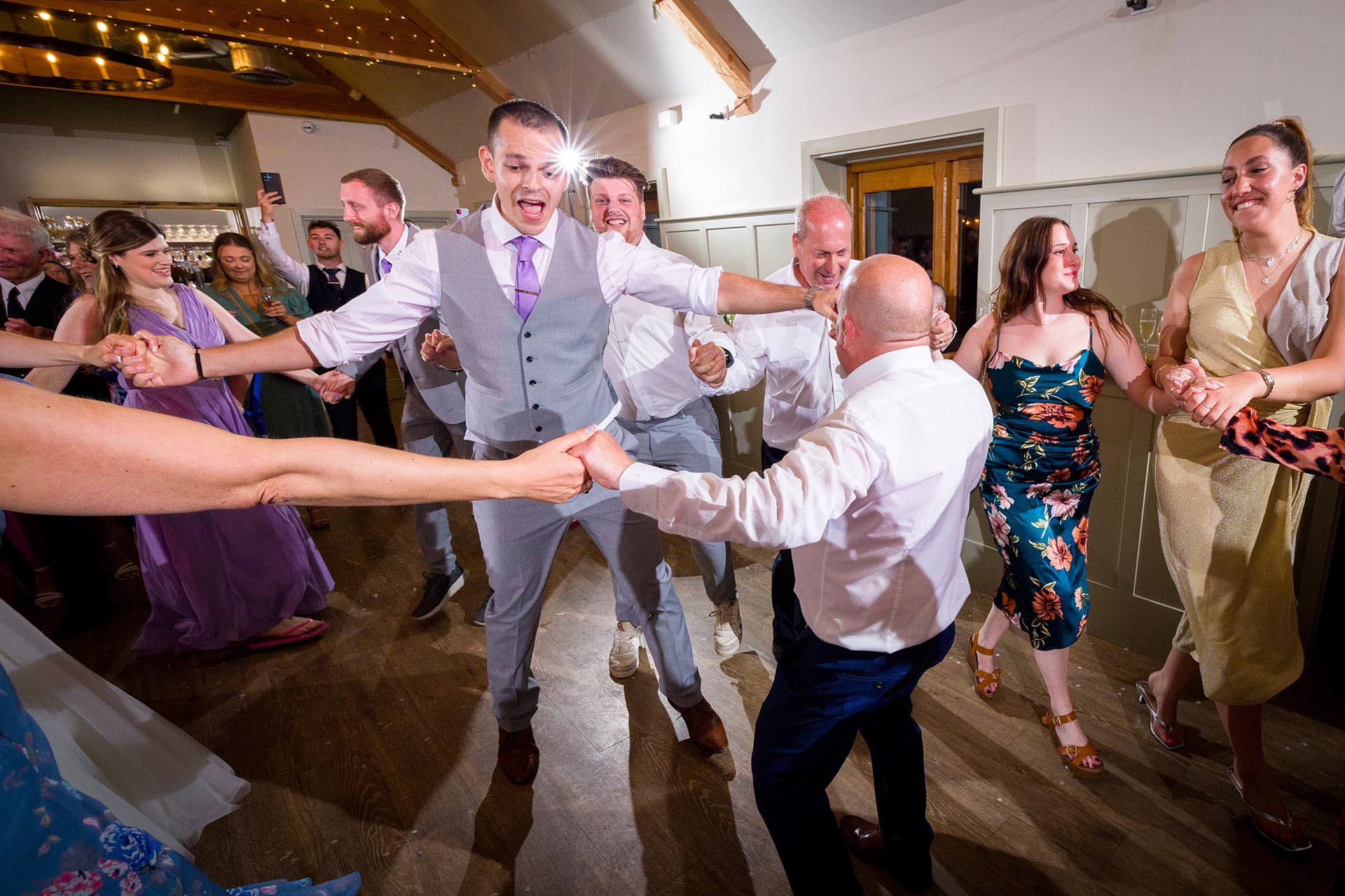 Colourful photograph of groom and guests dancing at Apton Hall, Rochford, Essex