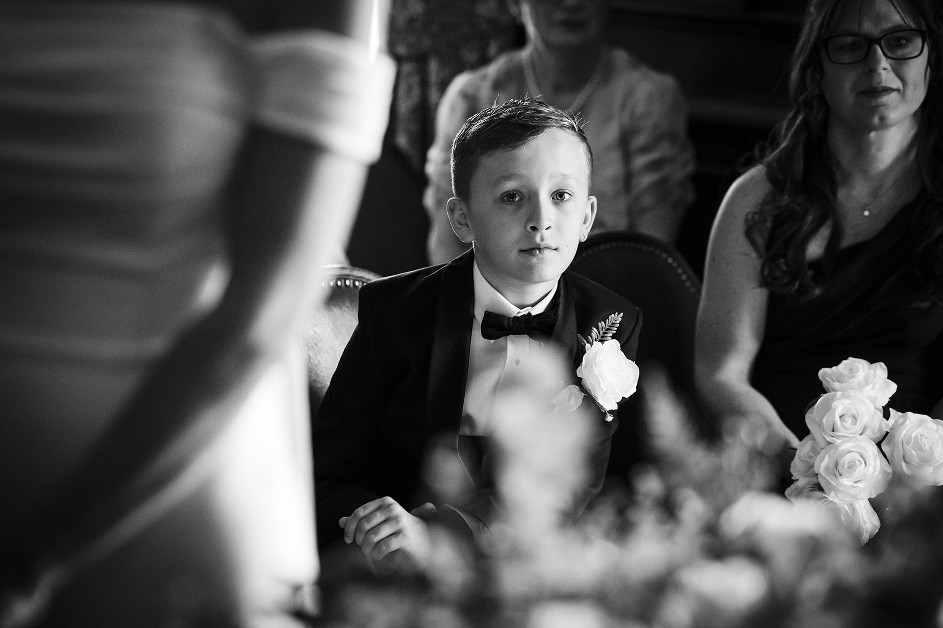 Black and white photograph of young groomsman during wedding ceremony at Braintree Town Hall, Braintree, Essex