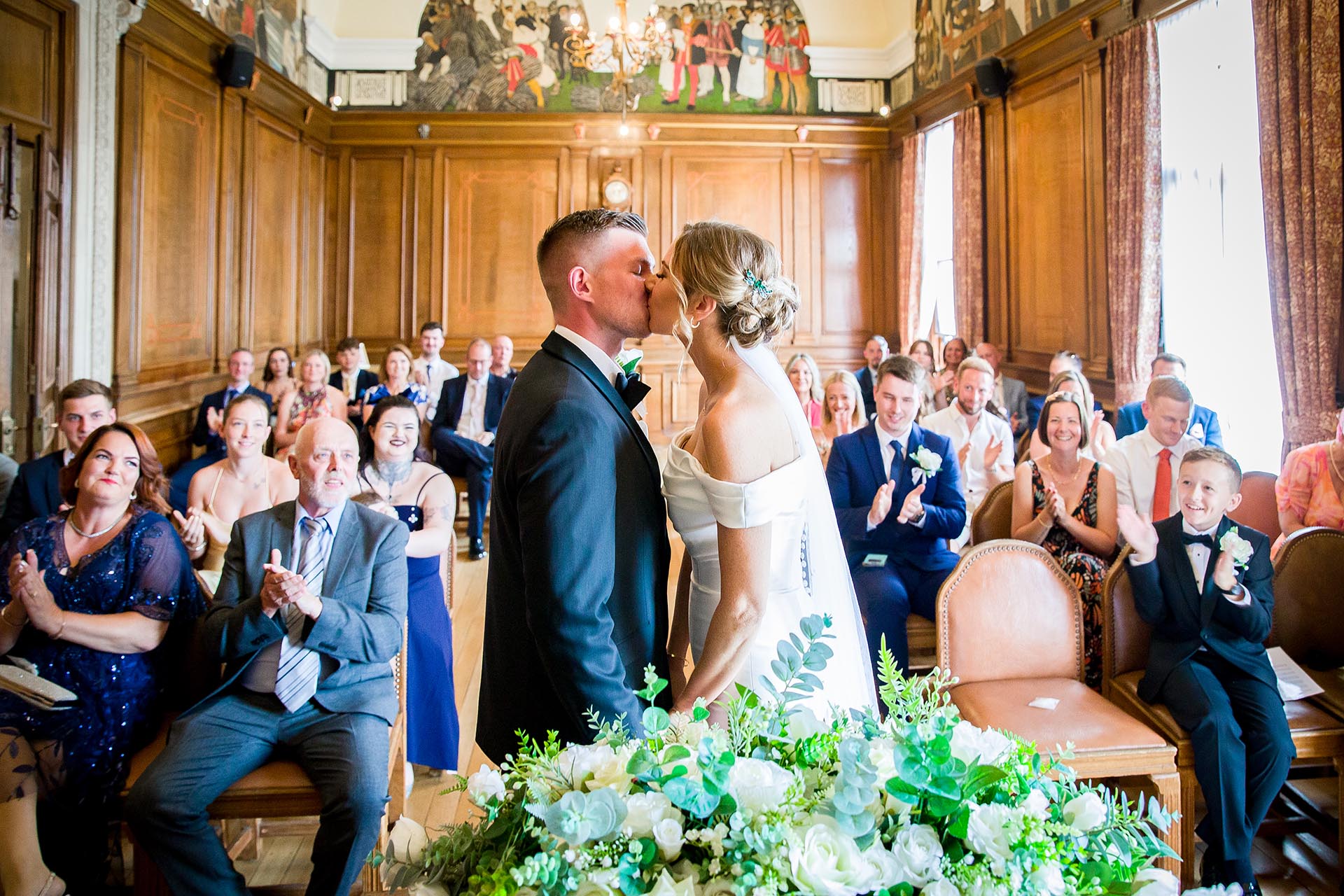 Photograph of bride and groom kissing with wedding guests applauding at Braintree Town Hall, Braintree, Essex