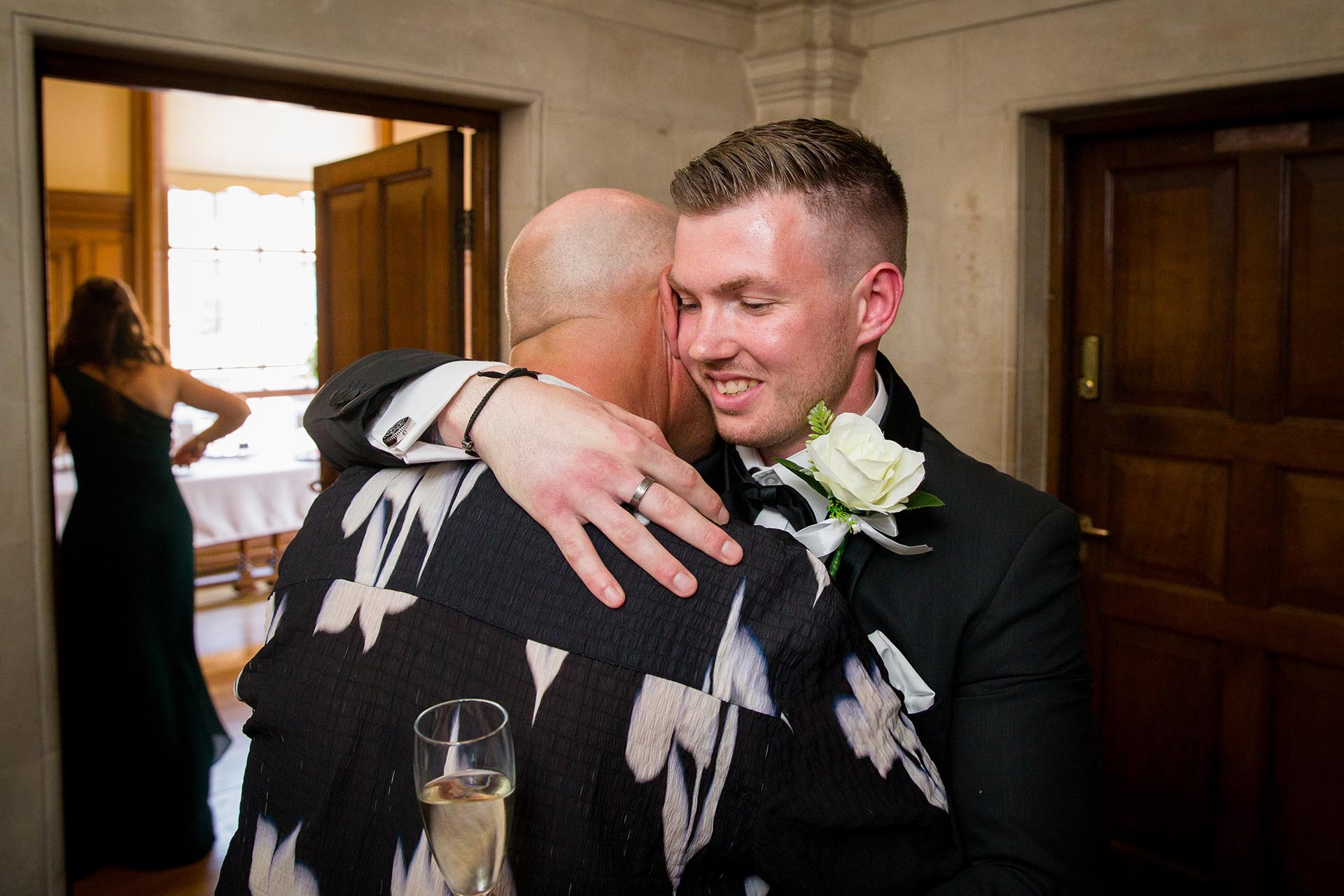 Photograph of groom hugging a wedding guest