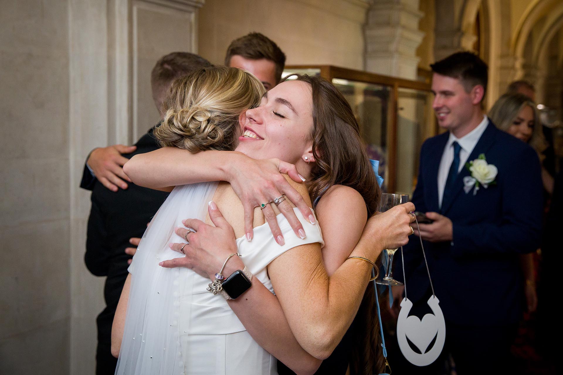 Photograph of a wedding guest hugging a bride