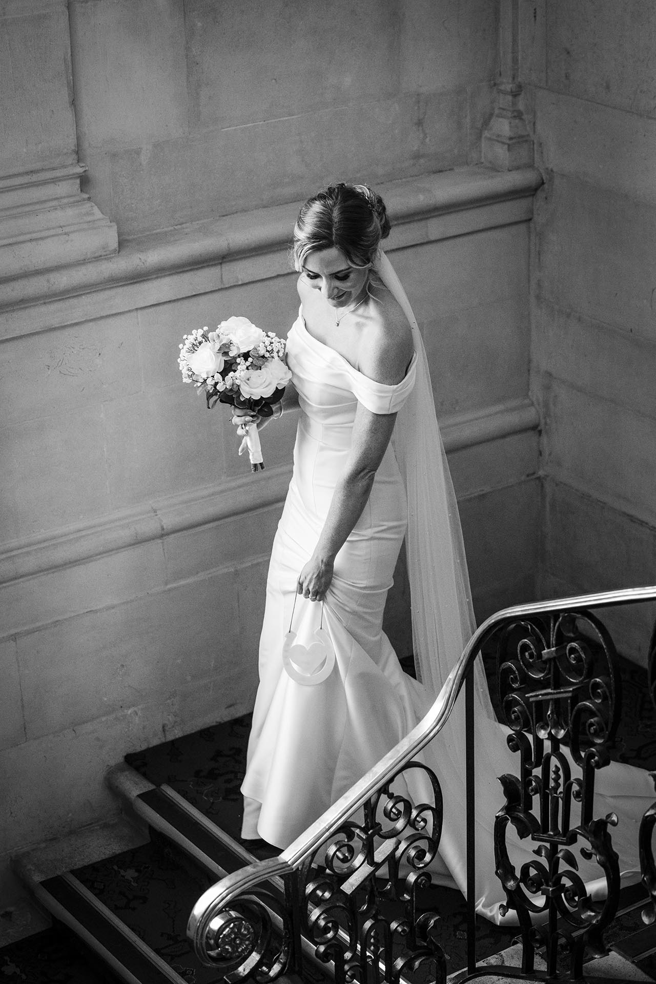 Black and white photograph of a bride walking down the stairs at Braintree Town Hall, Braintree, Essex