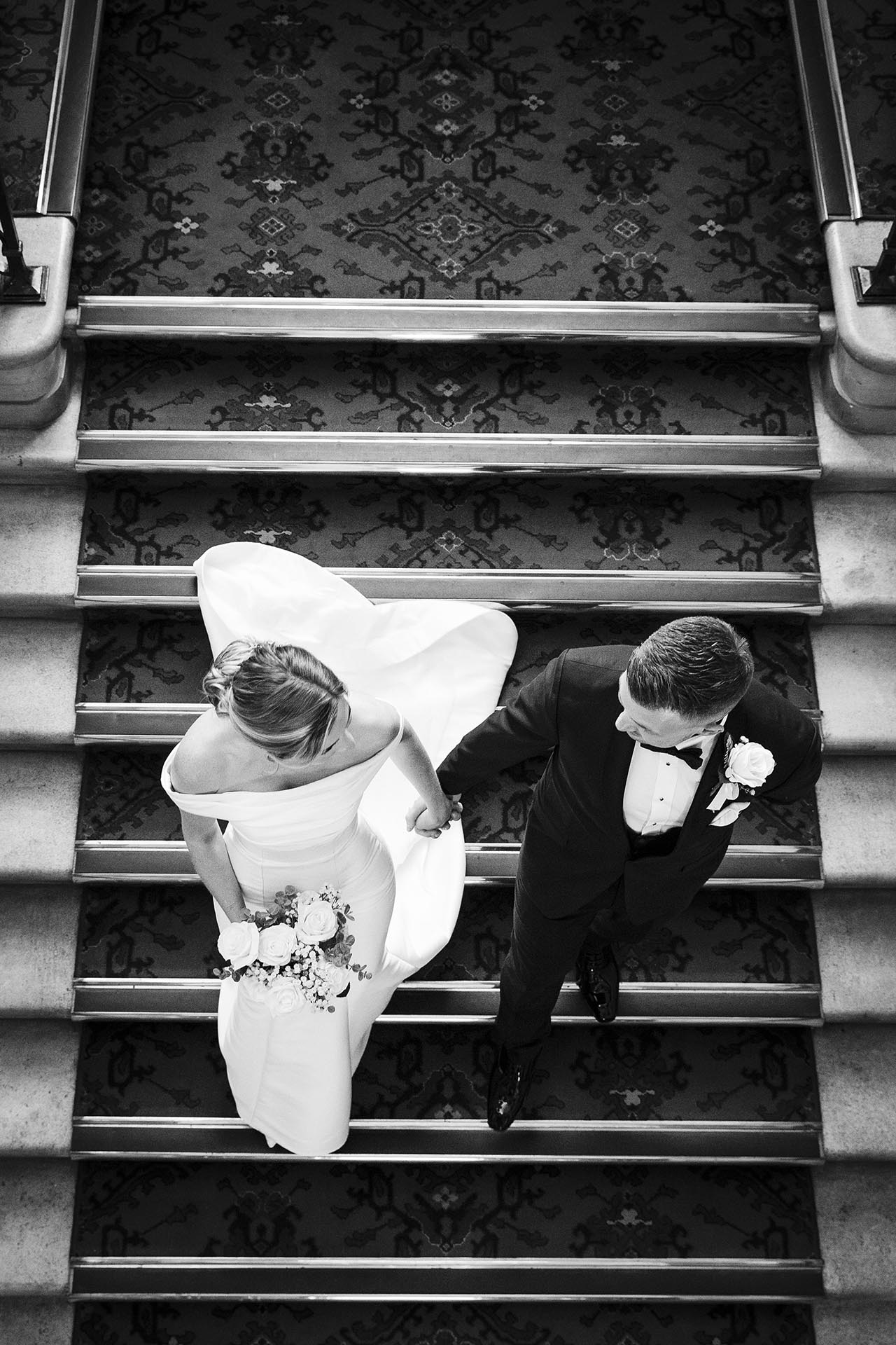 Black and white photograph of bride and groom walking down the staircase at Braintree Town Hall, Braintree, Essex