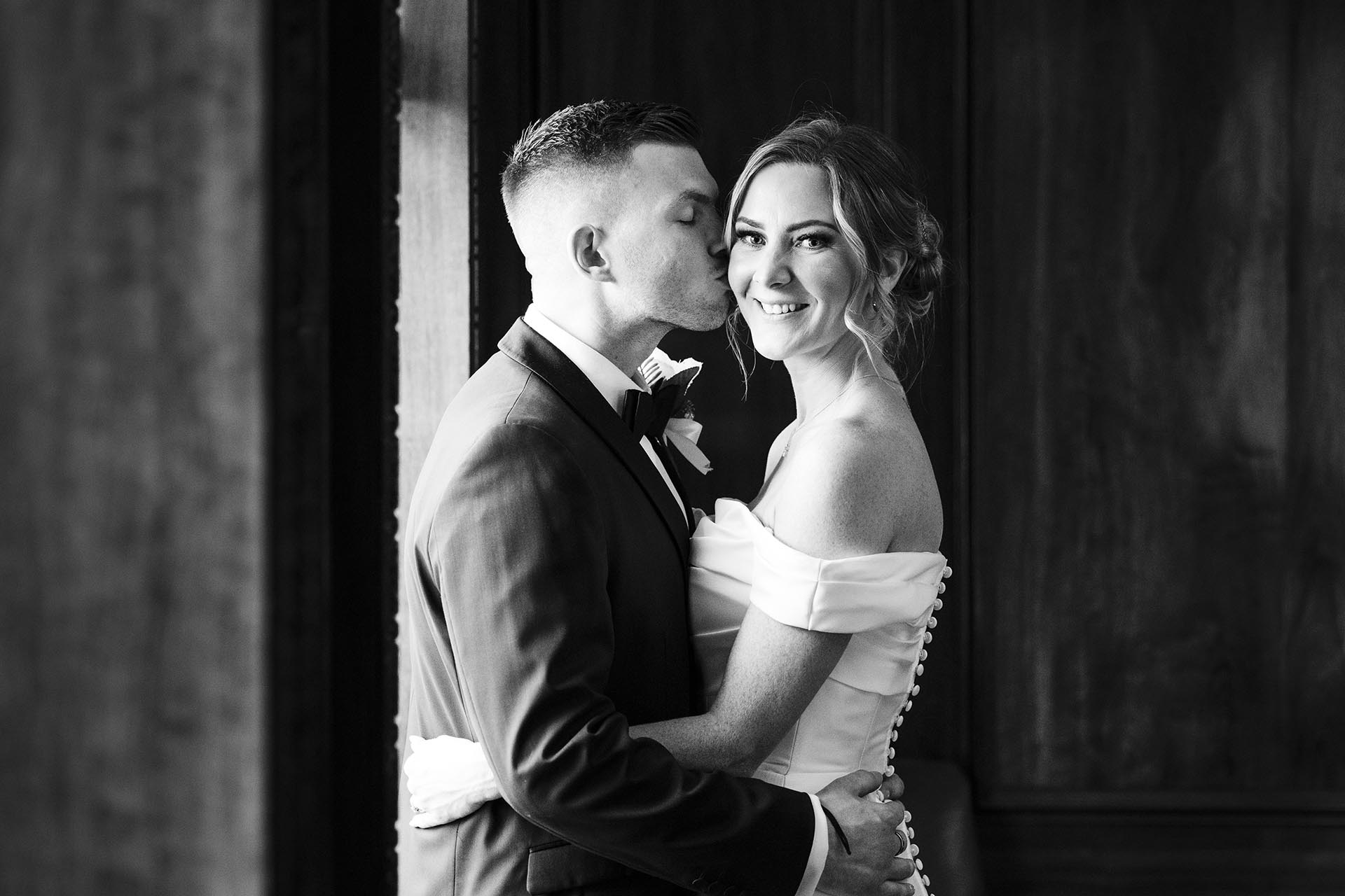 Black and white photograph of the groom kissing the bride at Braintree Town Hall, Braintree, Essex