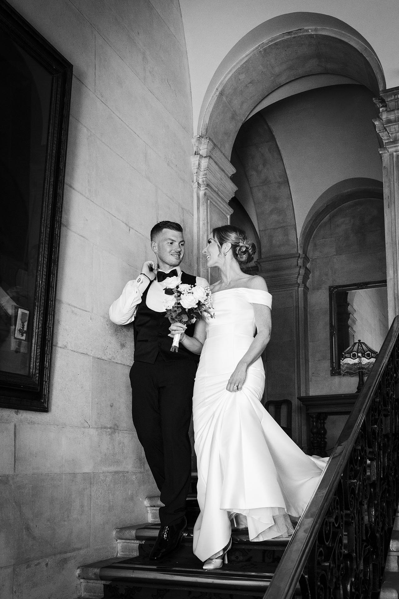 Black and white photograph of bride and groom walking down the staircase at Braintree Town Hall, Braintree, Essex