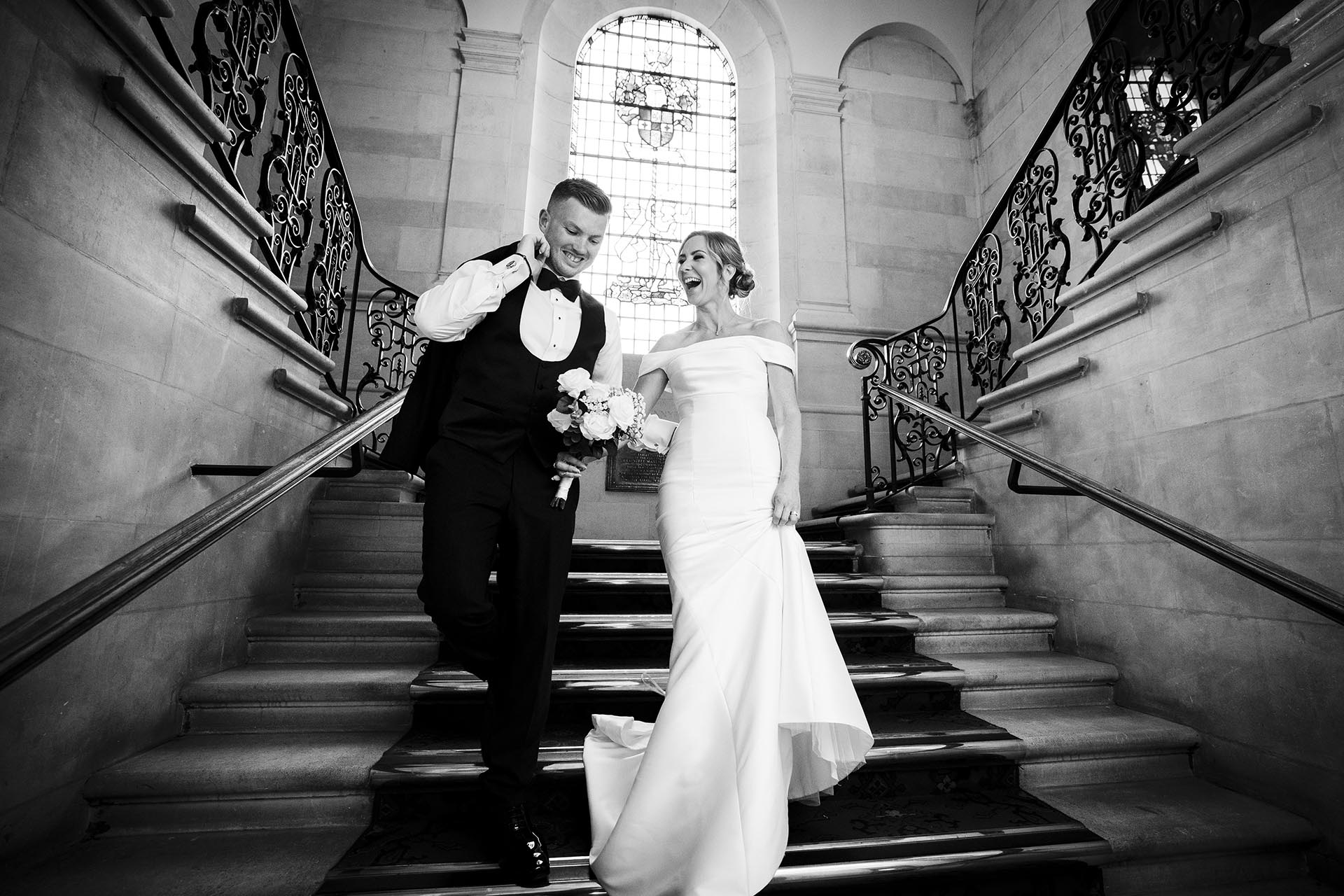 Black and white photograph of bride and groom walking down the staircase at Braintree Town Hall, Braintree, Essex