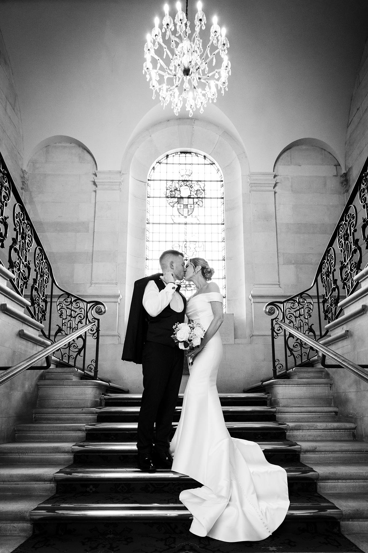Black and white photograph of bride and groom kissing on the staircase at Braintree Town Hall, Braintree, Essex