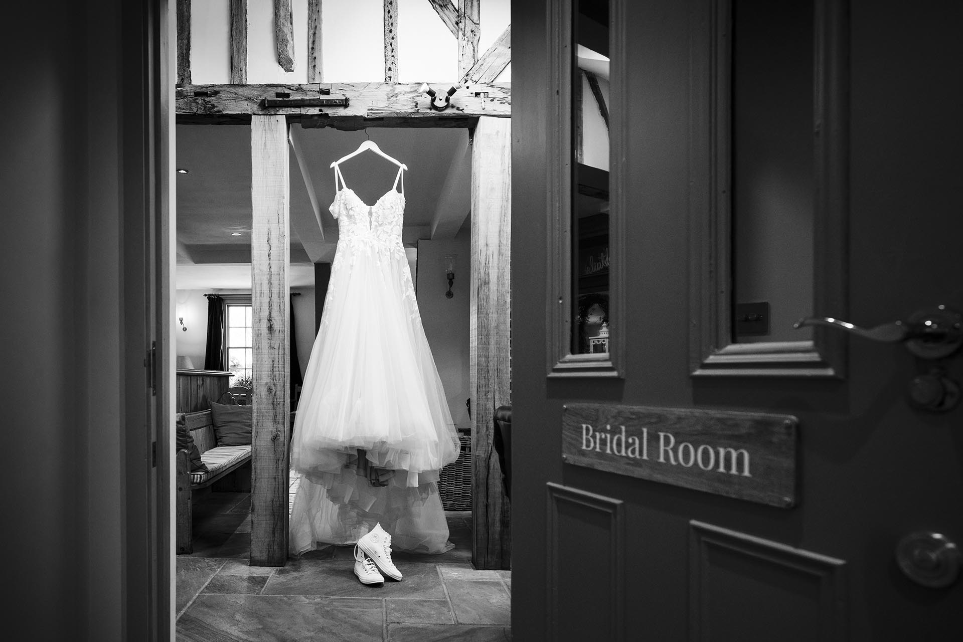 Black and white photograph of bride's wedding dress hanging up in The Compasses at Pattiswick bridal room