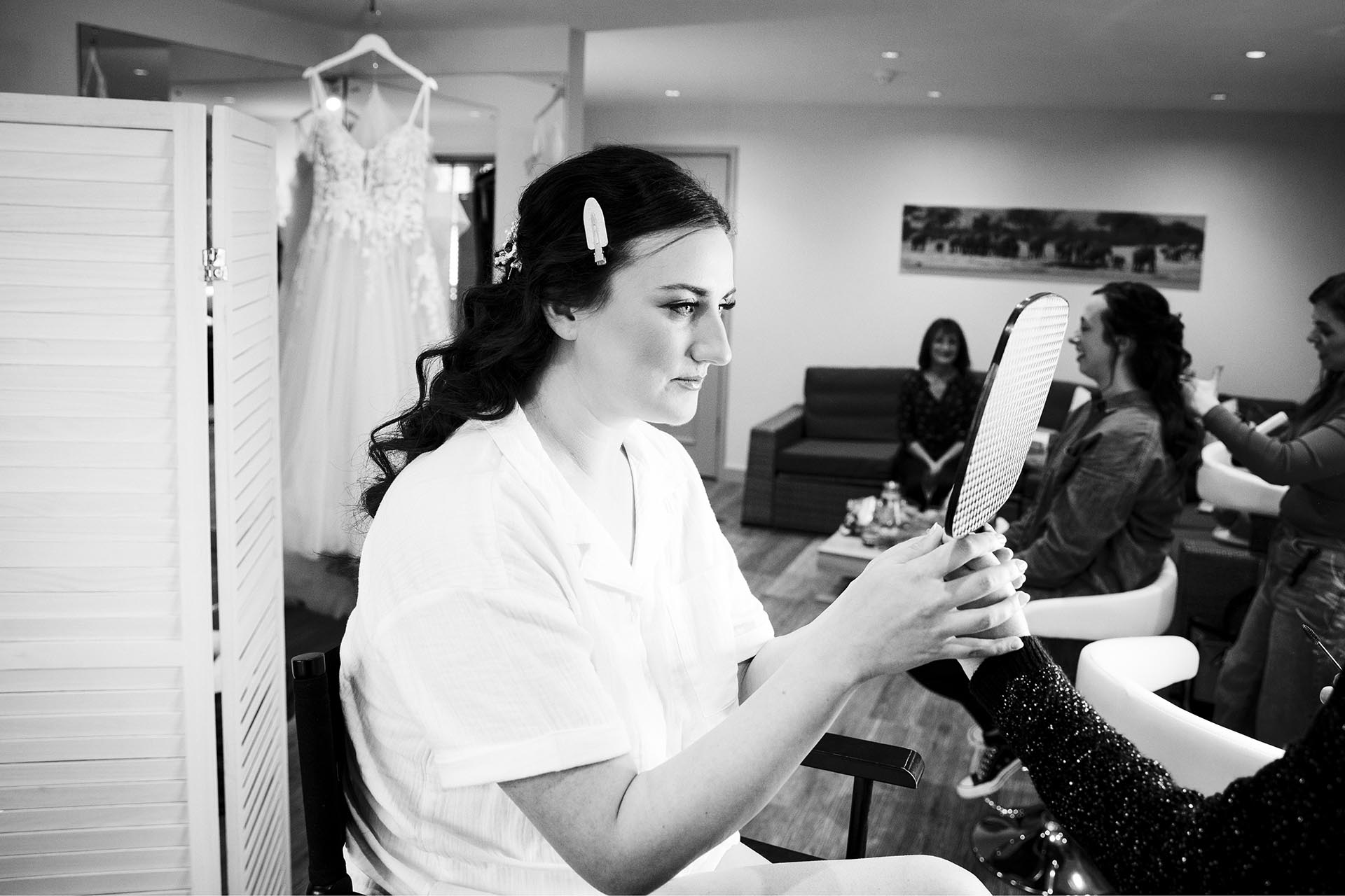 Black and white Photograph of bride checking her make-up in a hand-mirror