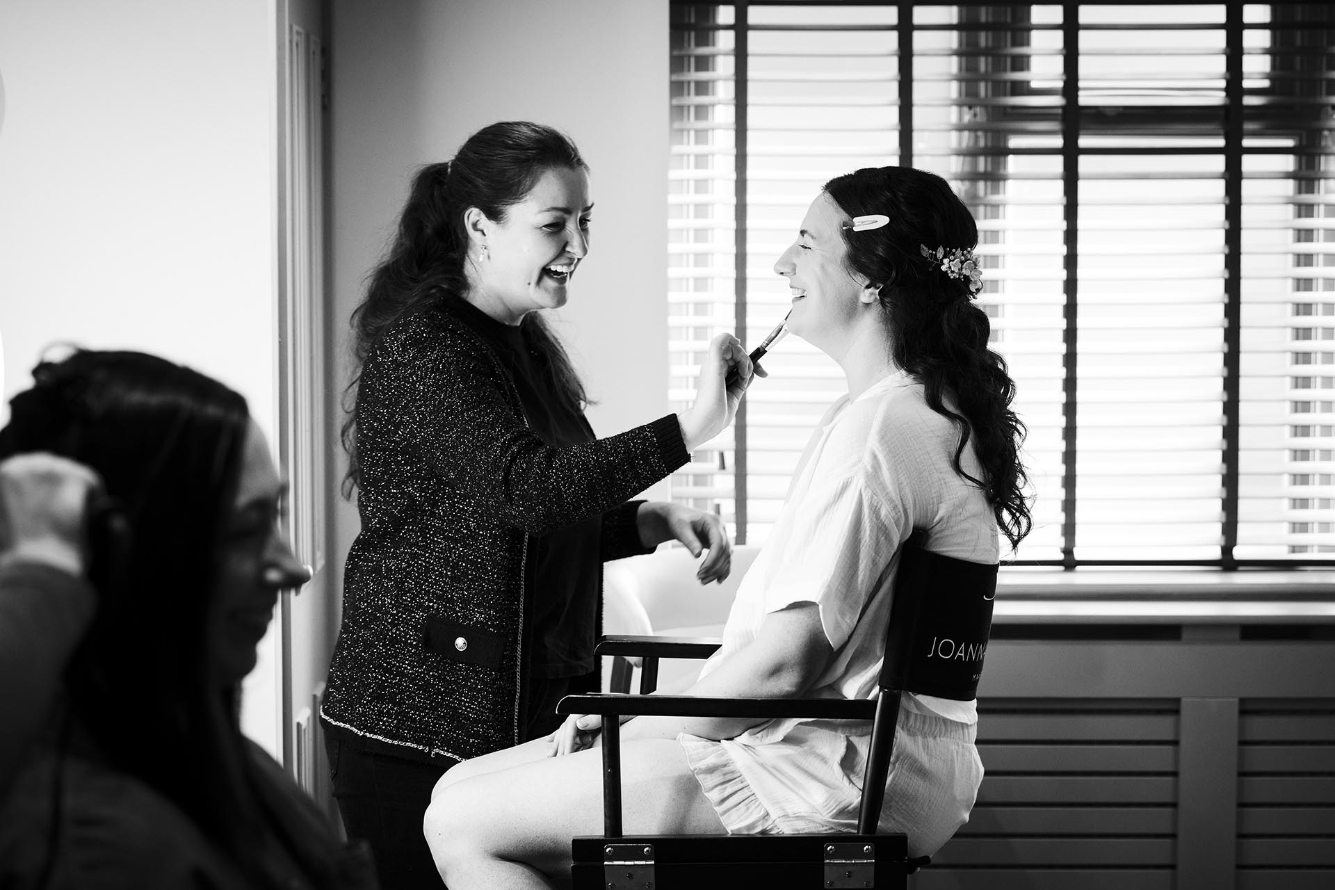 Black and white photograph of bride having her make-up applied