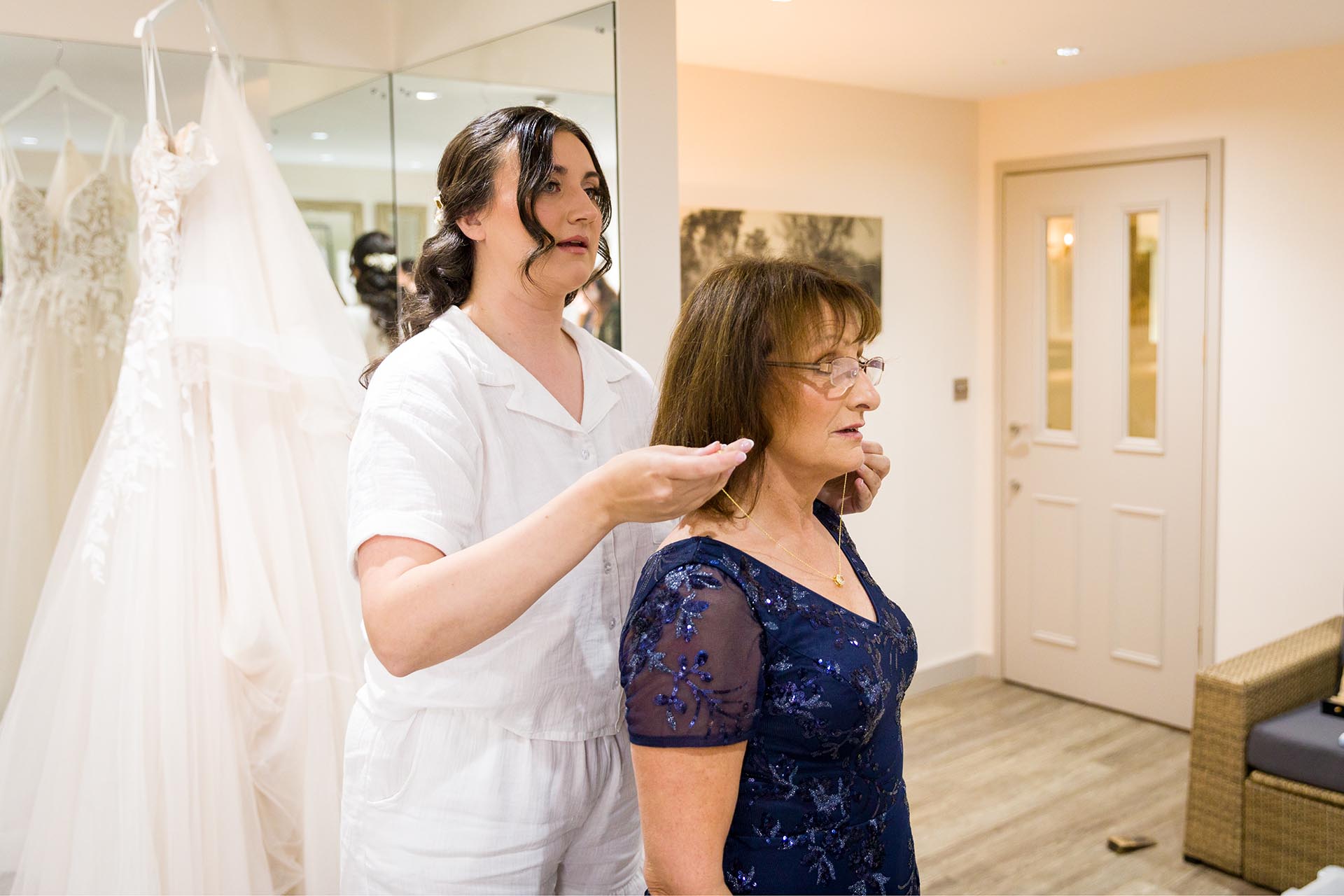 Photograph of bride helping her mother with jewellery in the bridal room at The Compasses at Pattiswick