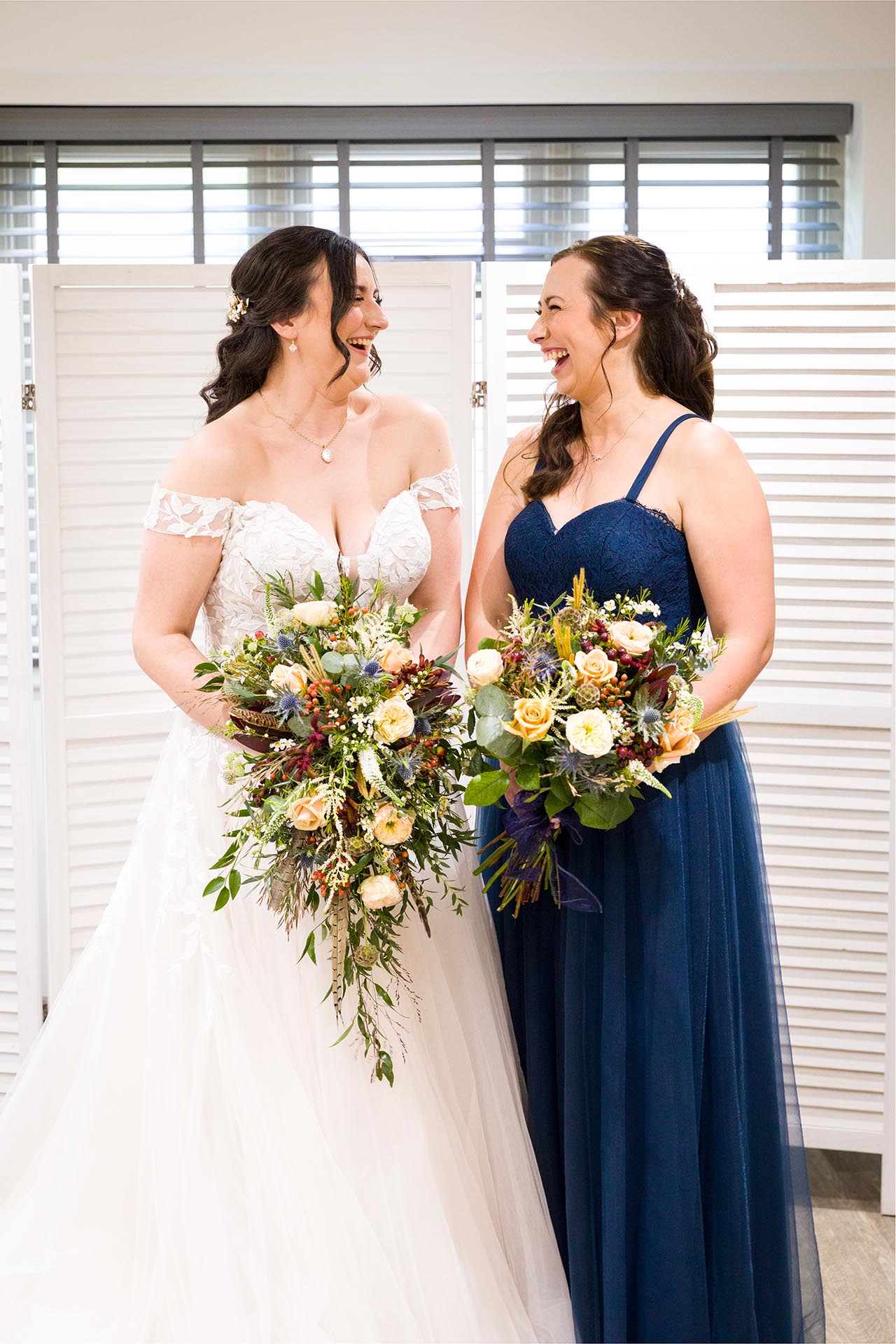 Photograph of bride laughing with her bridesmaid in the bridal room at The Compasses at Pattiswick