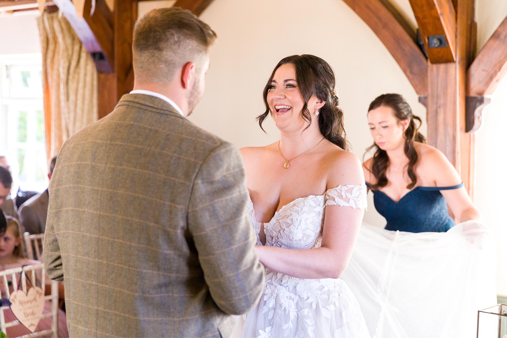 Photograph of bride smiling at her groom in the ceremony room at The Compasses at Pattiswick, Essex