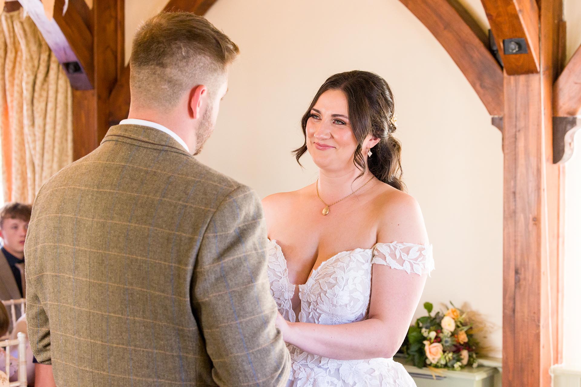 Photograph of bride smiling at her groom in the ceremony room at The Compasses at Pattiswick, Essex