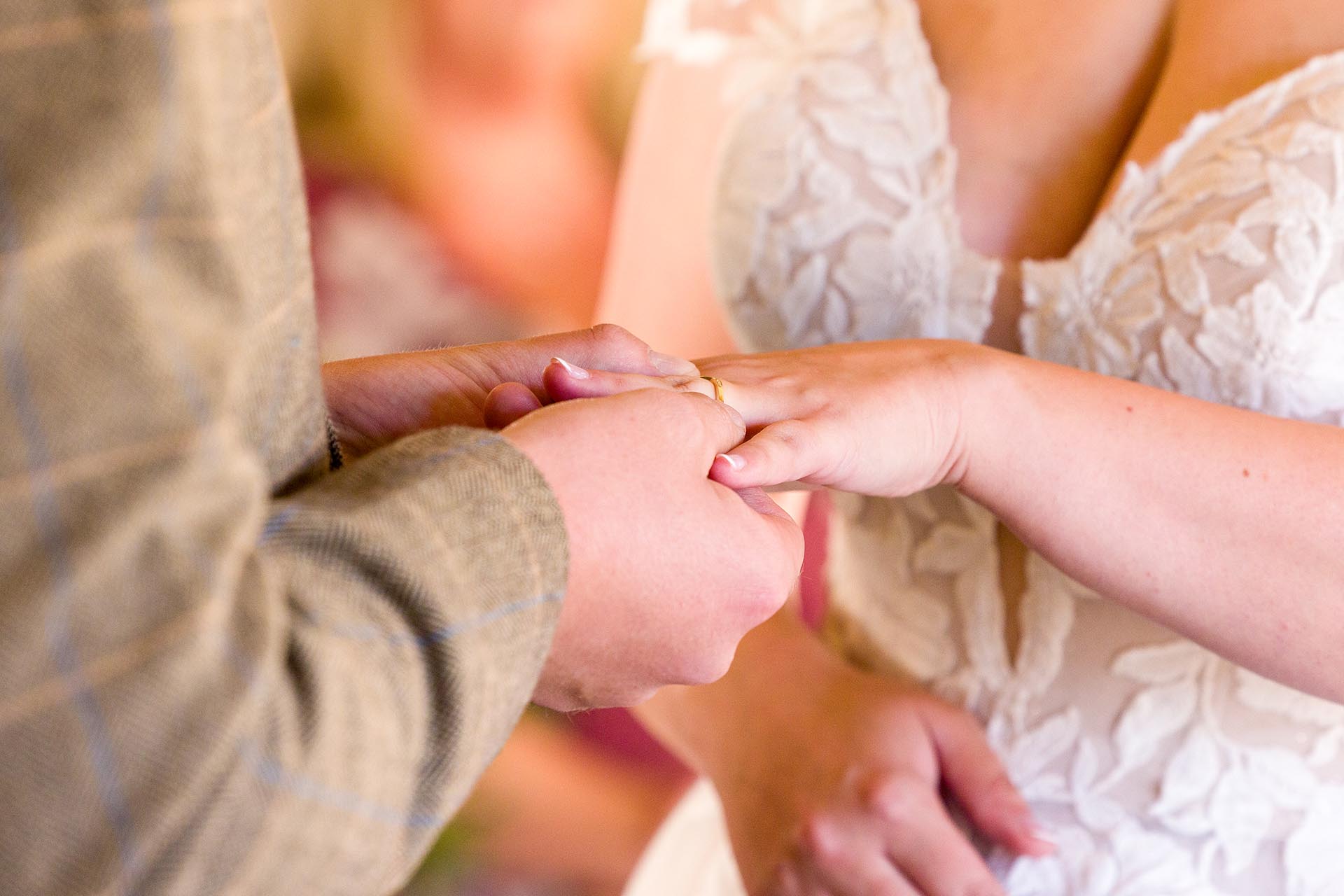 Close-up photograph of bride's wedding ring being put on