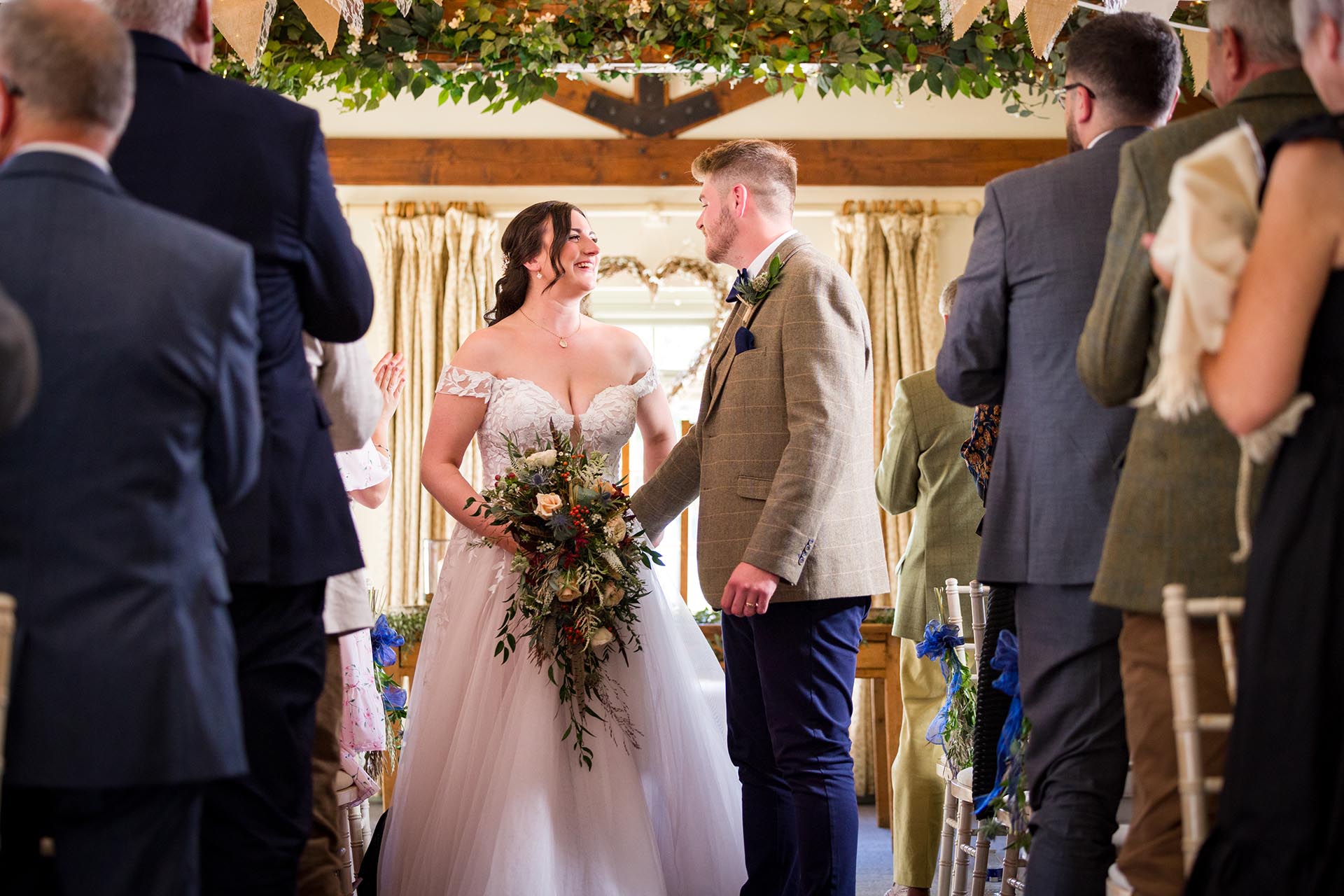 Photograph of bride and groom in the aisle in the ceremony room at The Compasses at Pattiswick, Essex