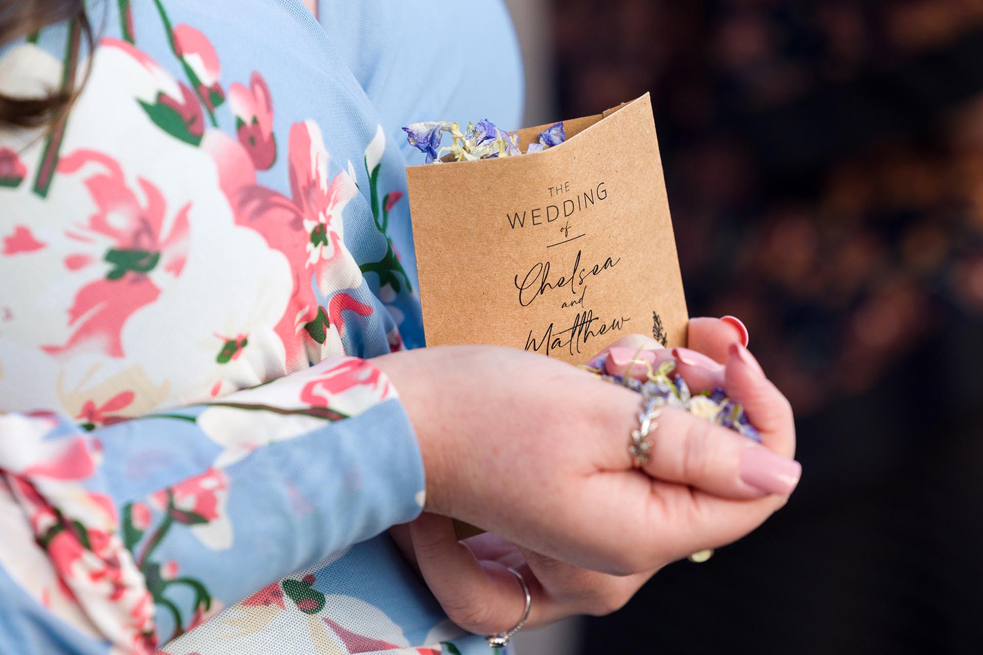 Photograph of a handful of natural flower petal confetti with a brown paper packet