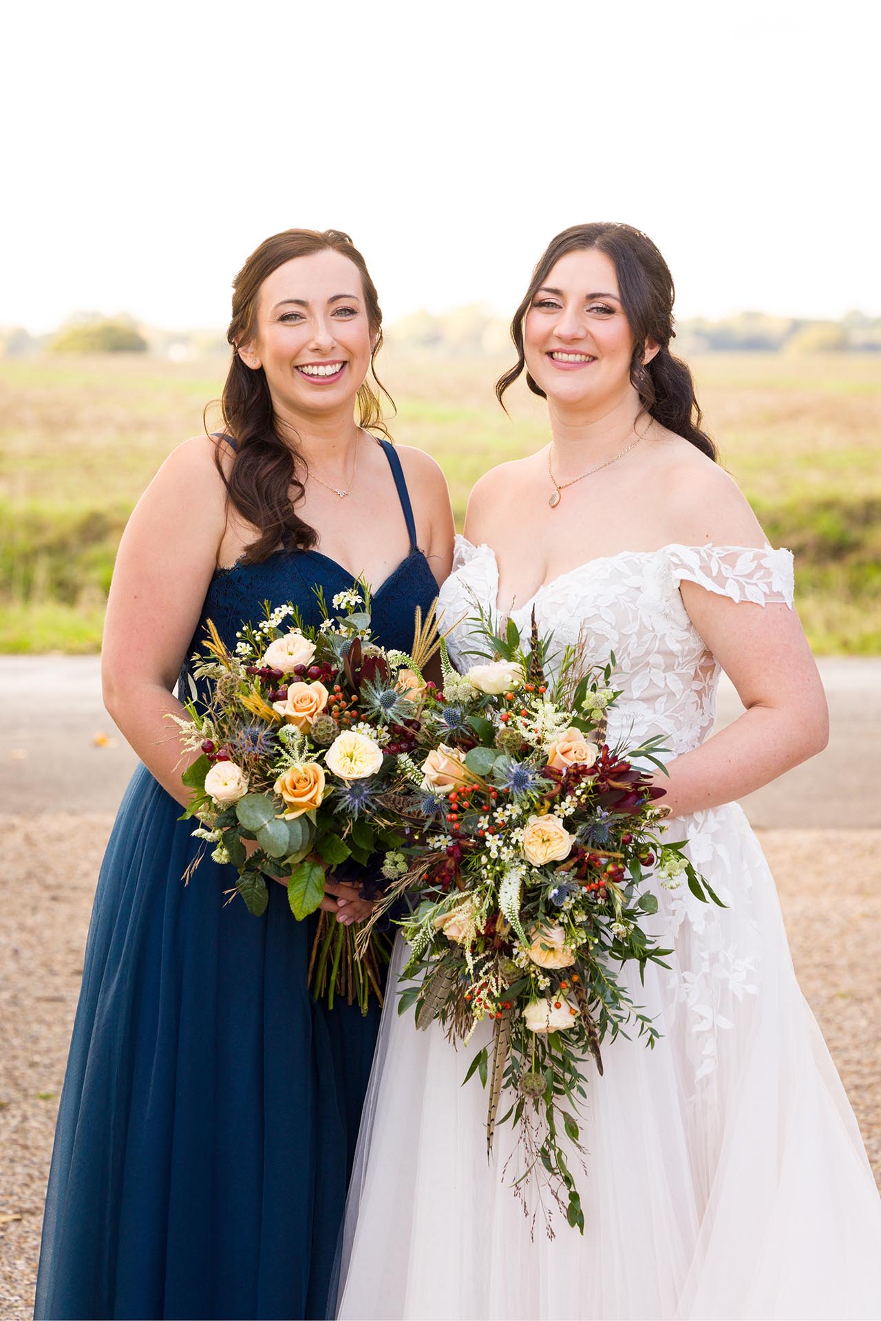 Photograph bride and her bridesmaid infront of fields at The Compasses at Pattiswick wedding venue