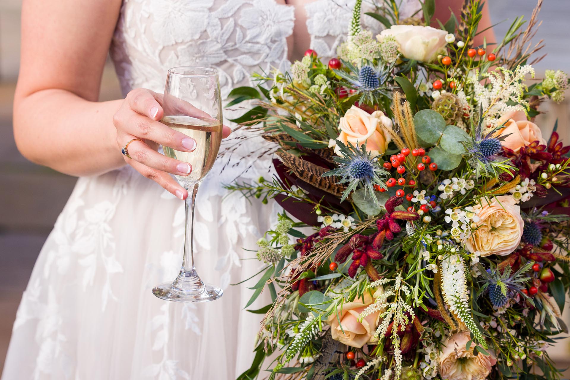 Close-up photograph of bride holding a champagne flute and wedding bouquet