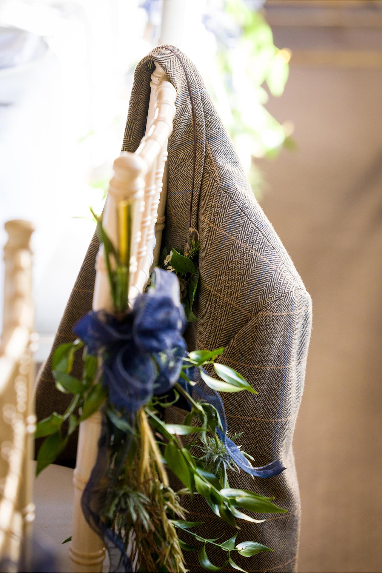 Photograph of groom's jacket hanging on chair during the wedding breakfast at The Compasses at Pattiswick