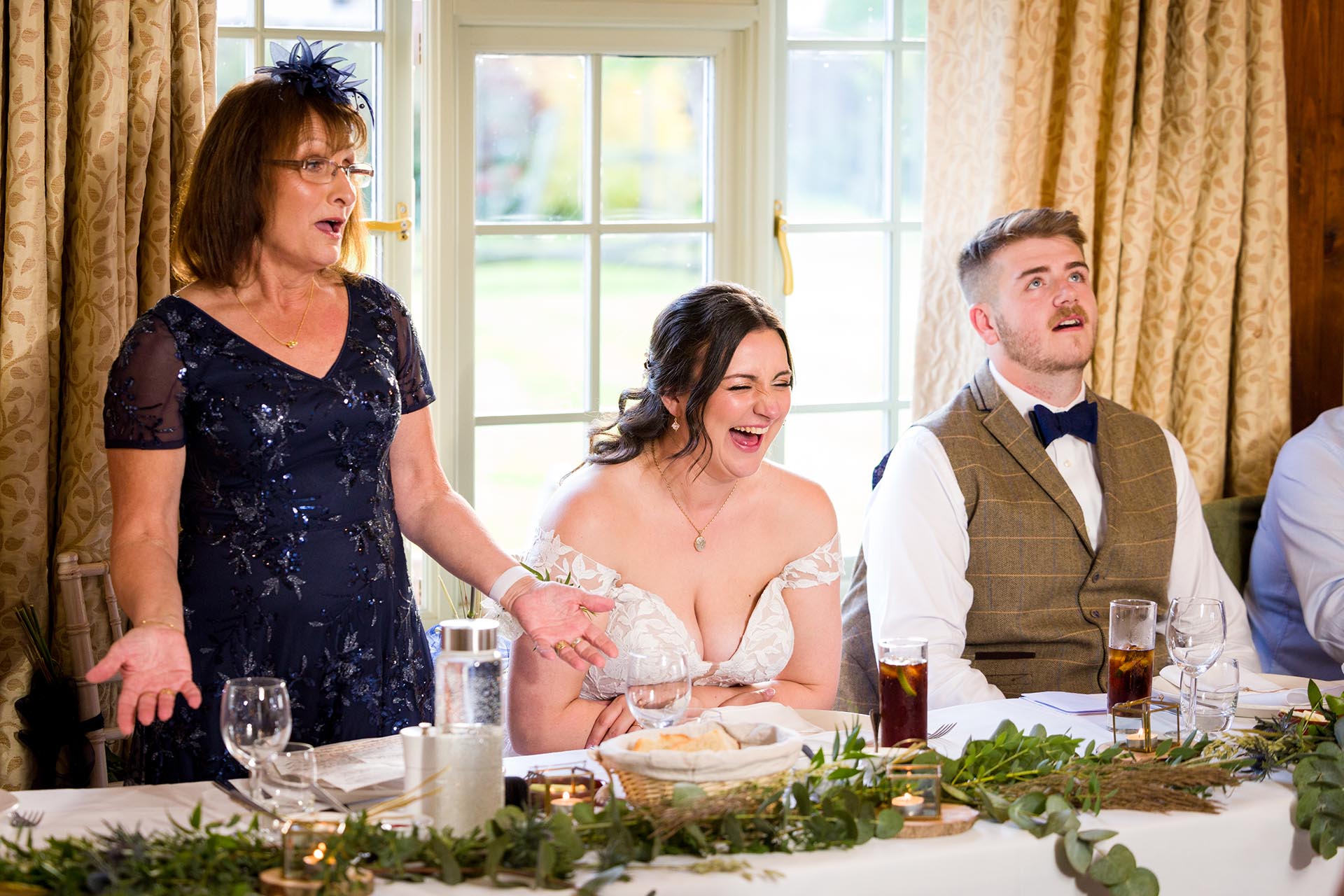 Photograph of bride laughing during speeches at The Compasses at Pattiswick