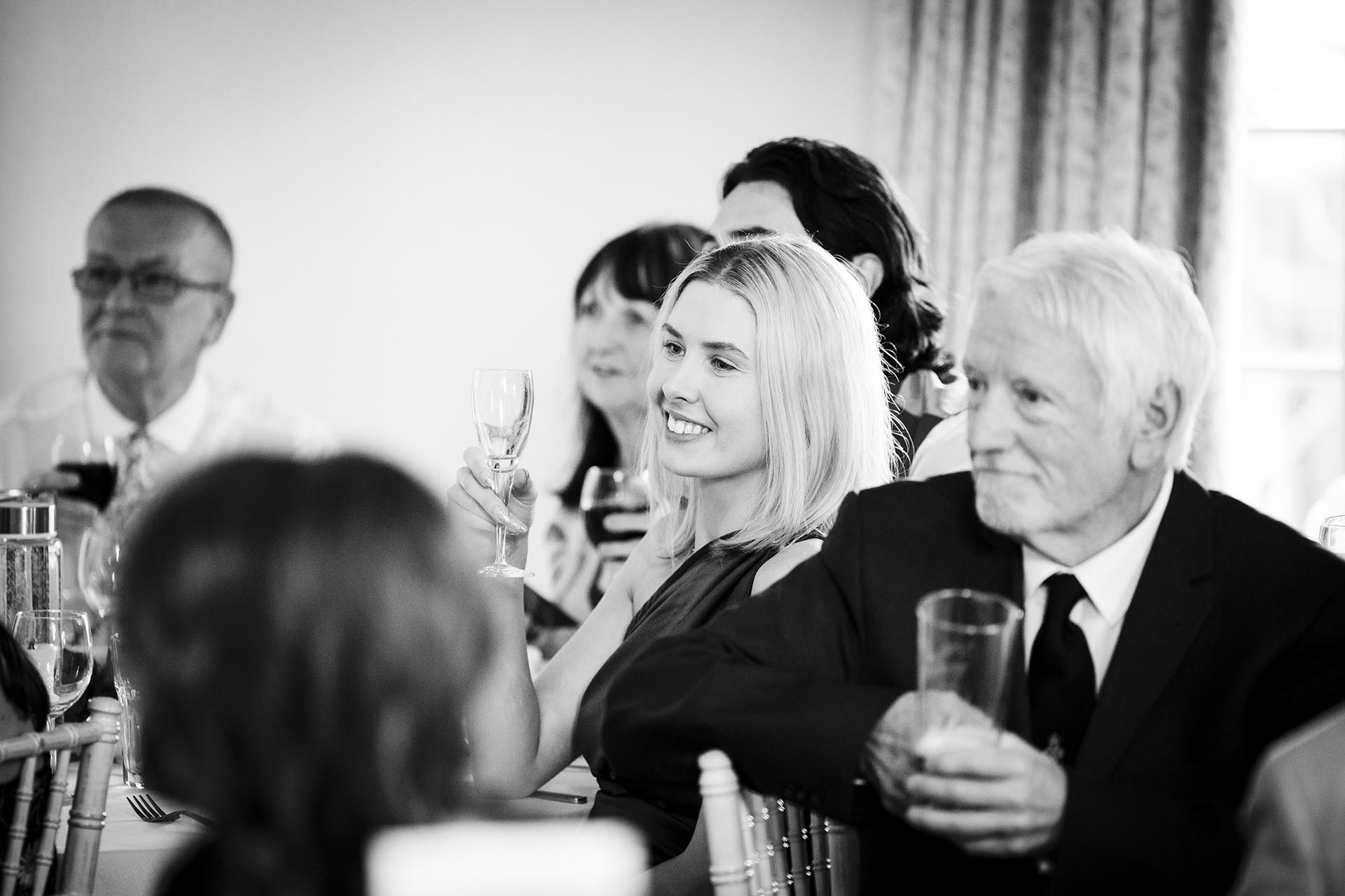 Black and white photograph of wedding guest raising glass for a toast