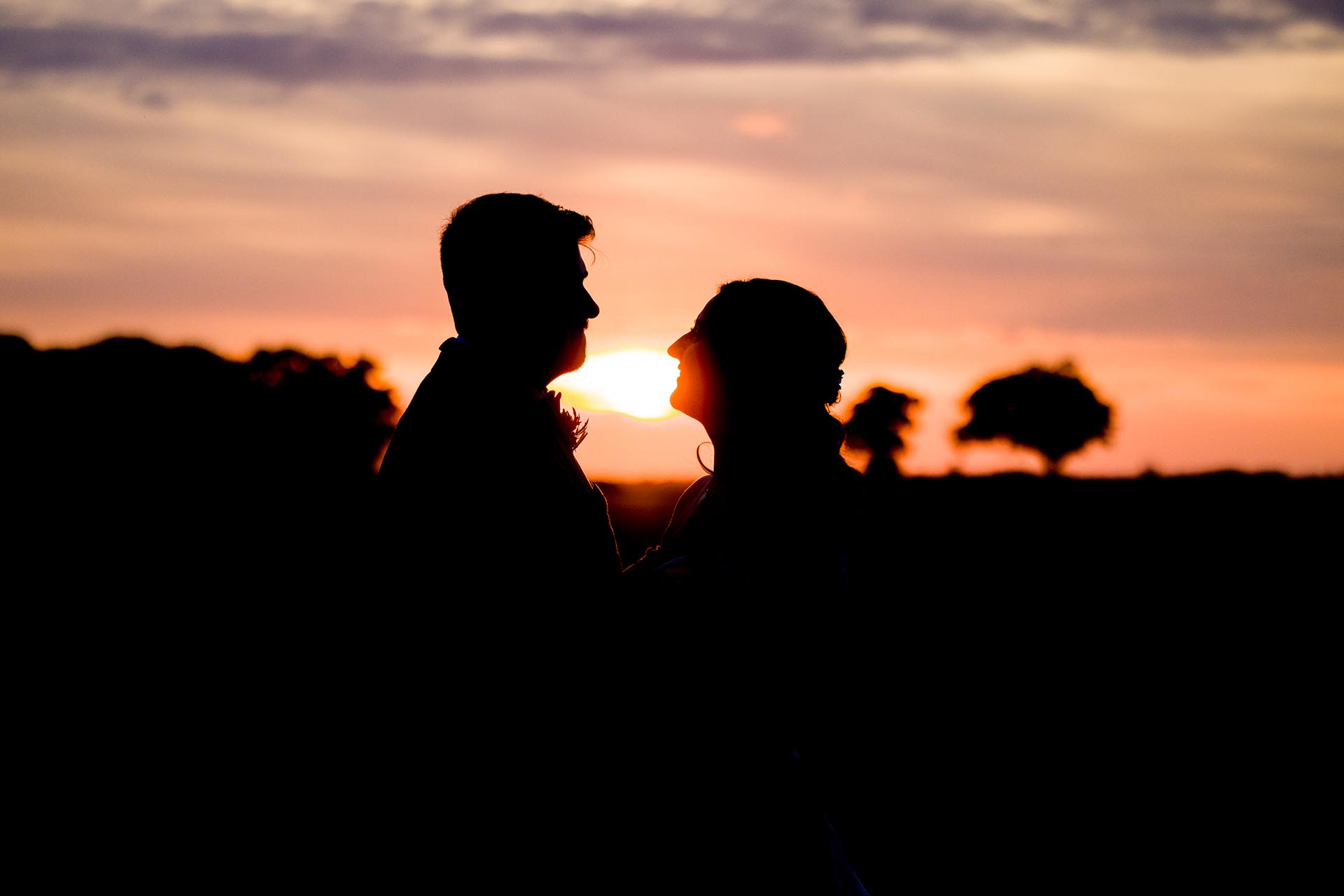 Photograph of bride and groom silhouetted infront of a sunset at The Compasses at Pattiswick