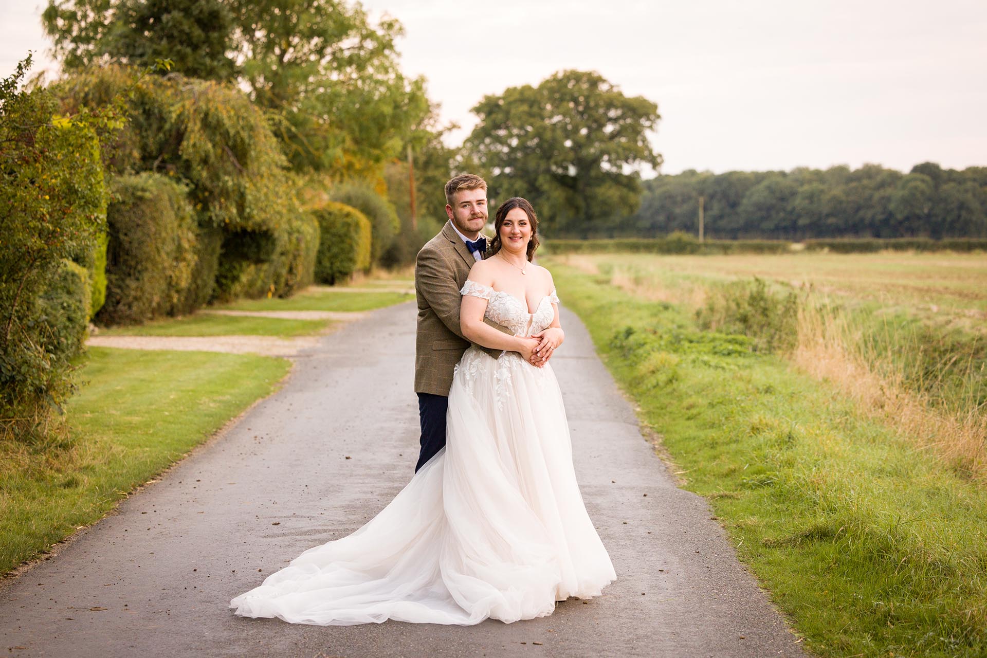 Photograph of bride and groom hugging in the lane outside The Compasses at Pattiswick