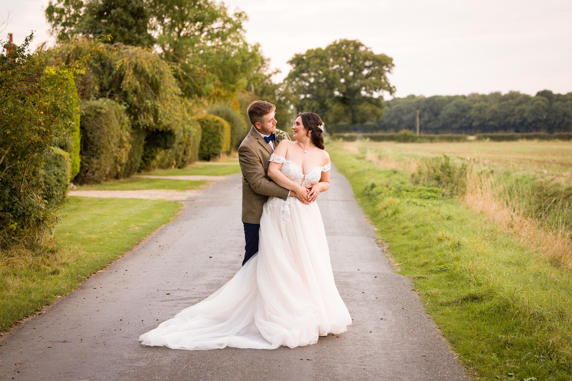 Photograph of bride and groom hugging in the lane outside The Compasses at Pattiswick