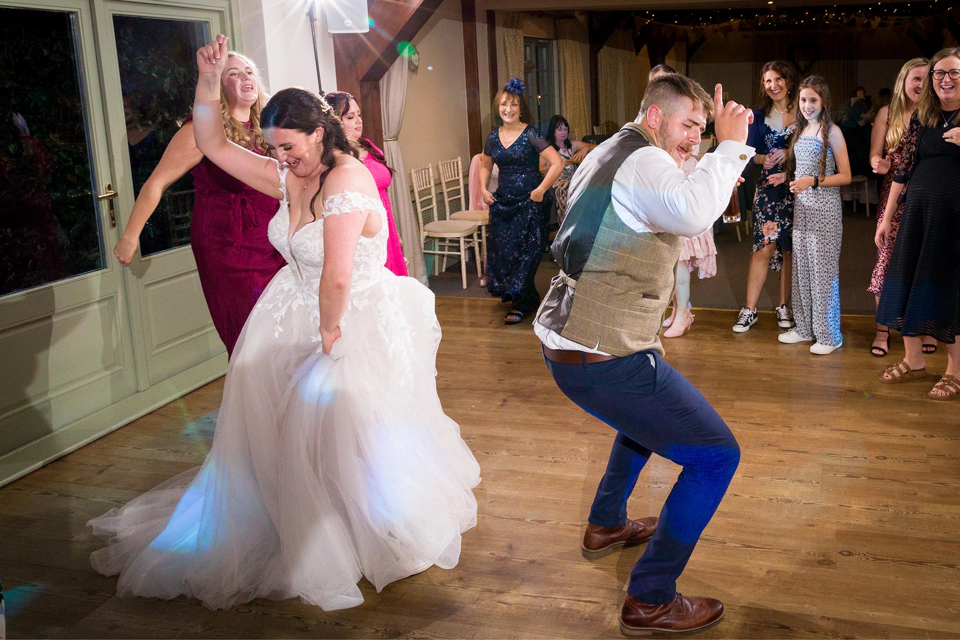 Photograph of bride and groom dancing amongst guests at The Compasses at Pattiswick
